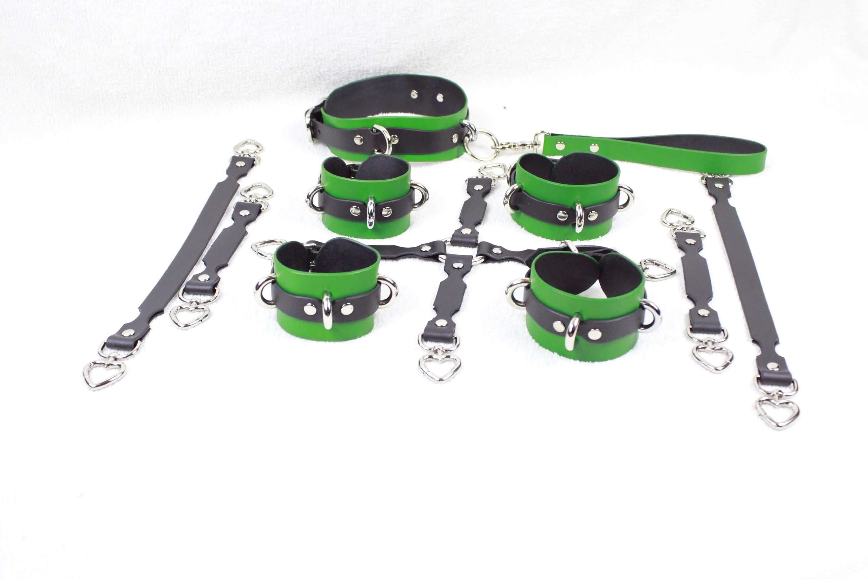 A collection of green and black leather restraints and straps, including a collar, harnesses, and straps, arranged on a white background.