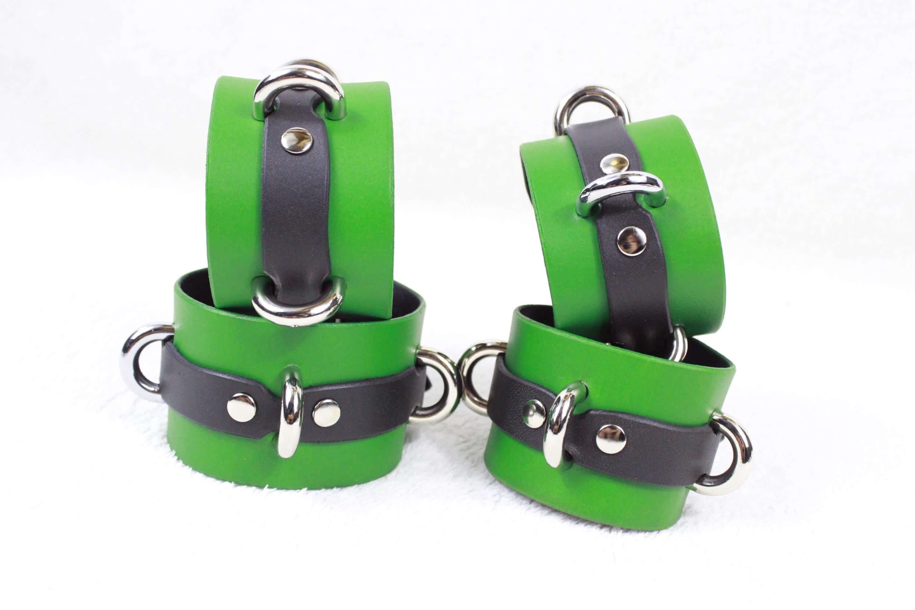 A pair of green and black leather wrist straps with silver buckles and clasps.