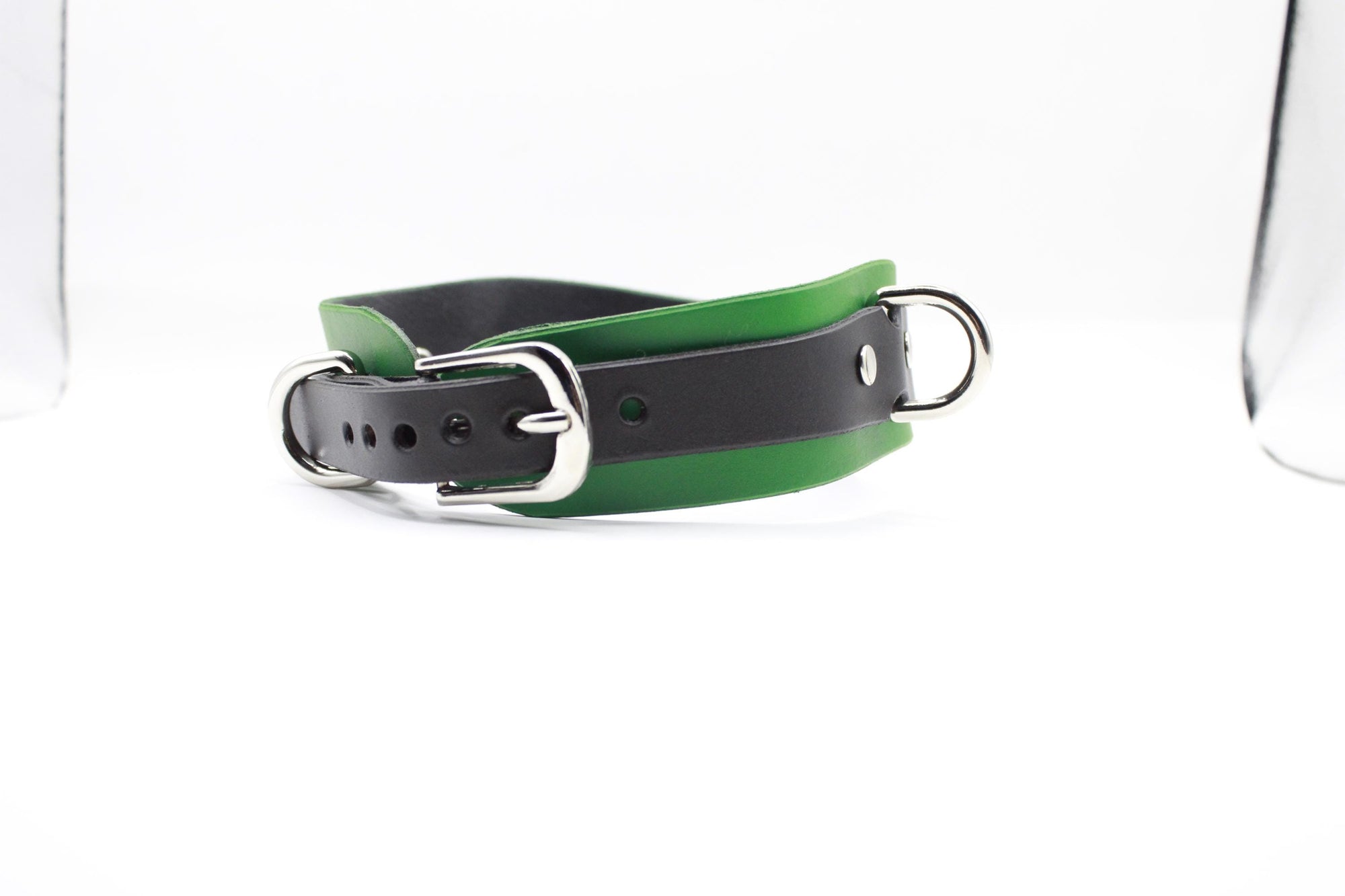 A black and green leather collar with a silver buckle is shown against a white background.