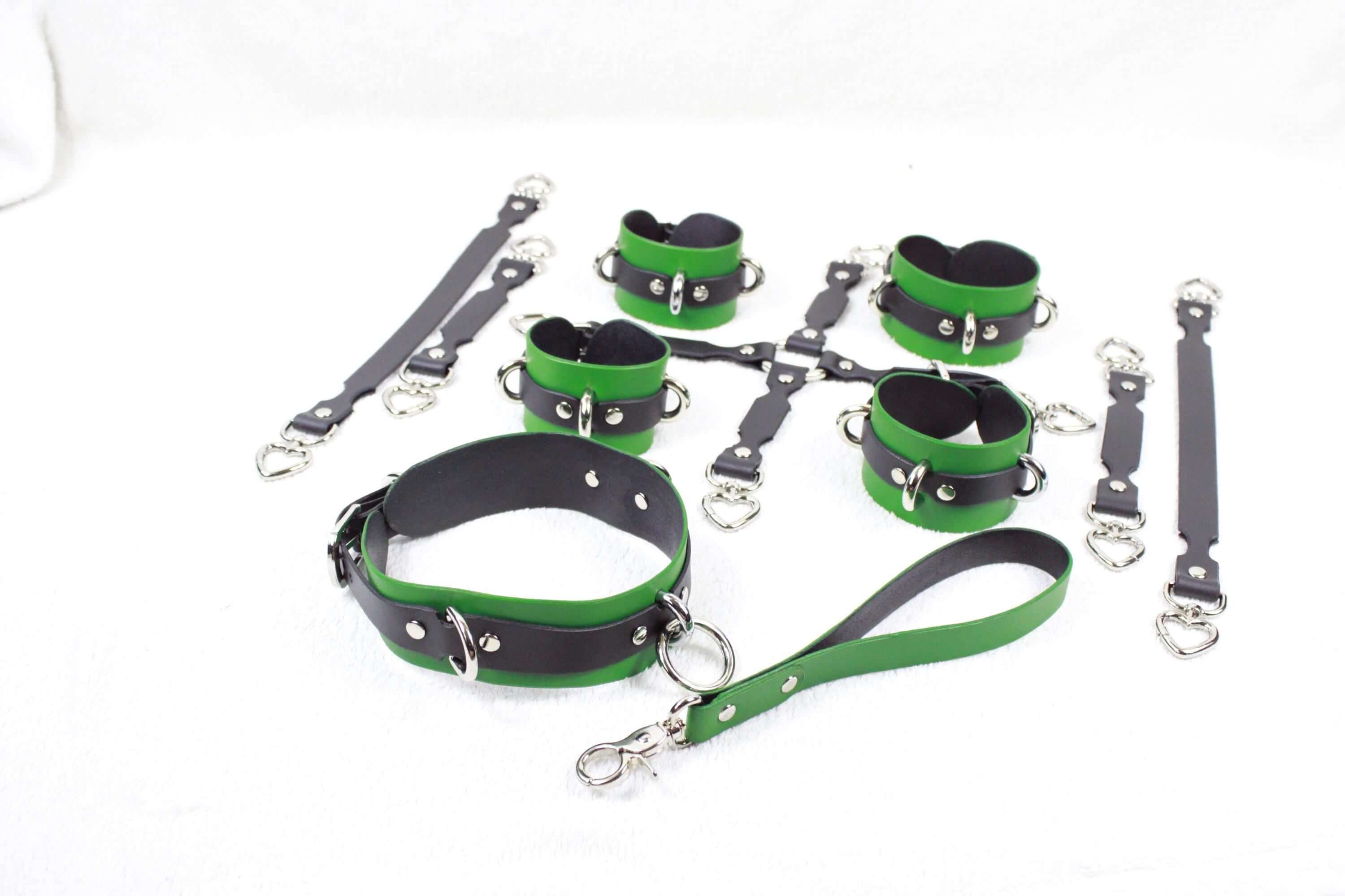 A collection of green and black leather restraints or restraints, including collars, straps, and handles, arranged on a white background.
