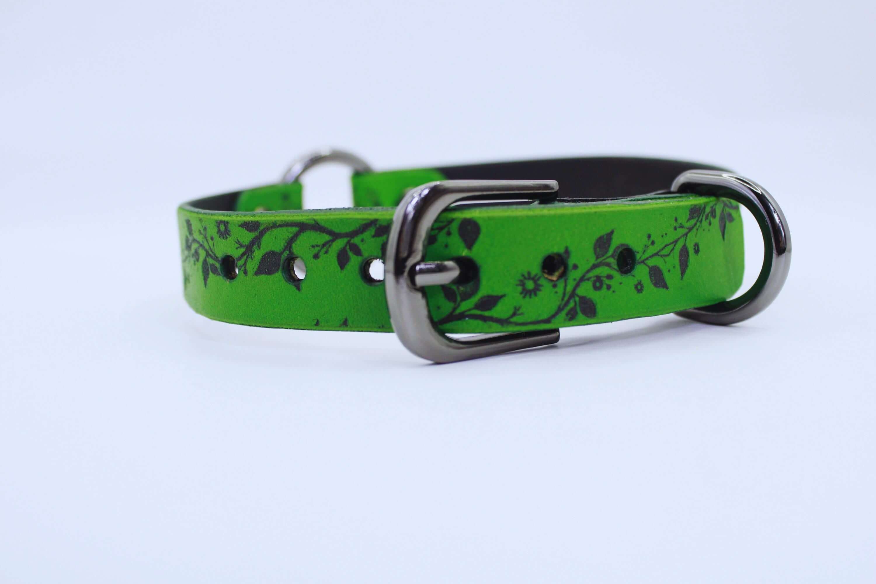 A green dog collar with a black leaf design on it.