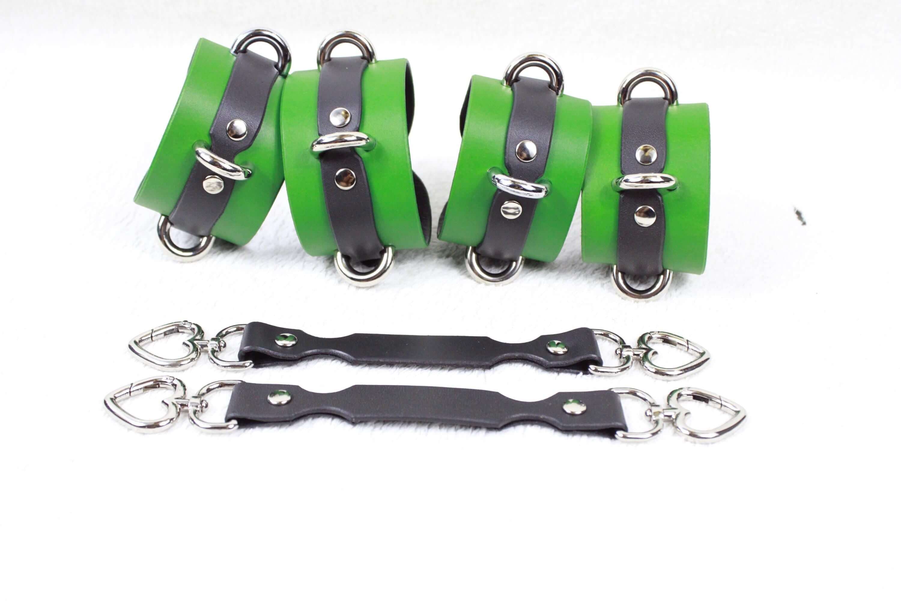 a pair of green and black leather straps with silver buckles, arranged on a white background.