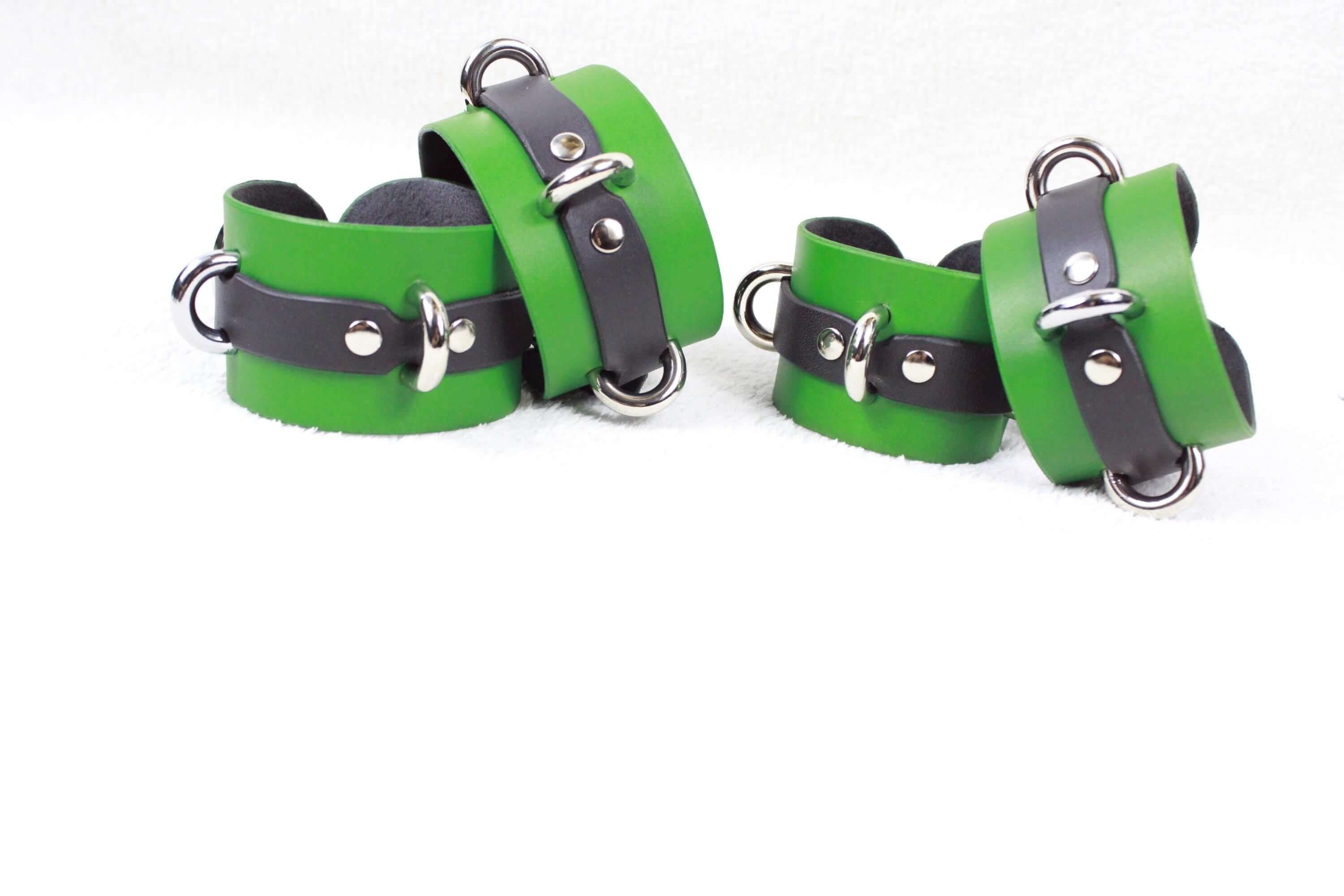 A group of green and black leather wristbands with metal buckles, arranged on a white background.