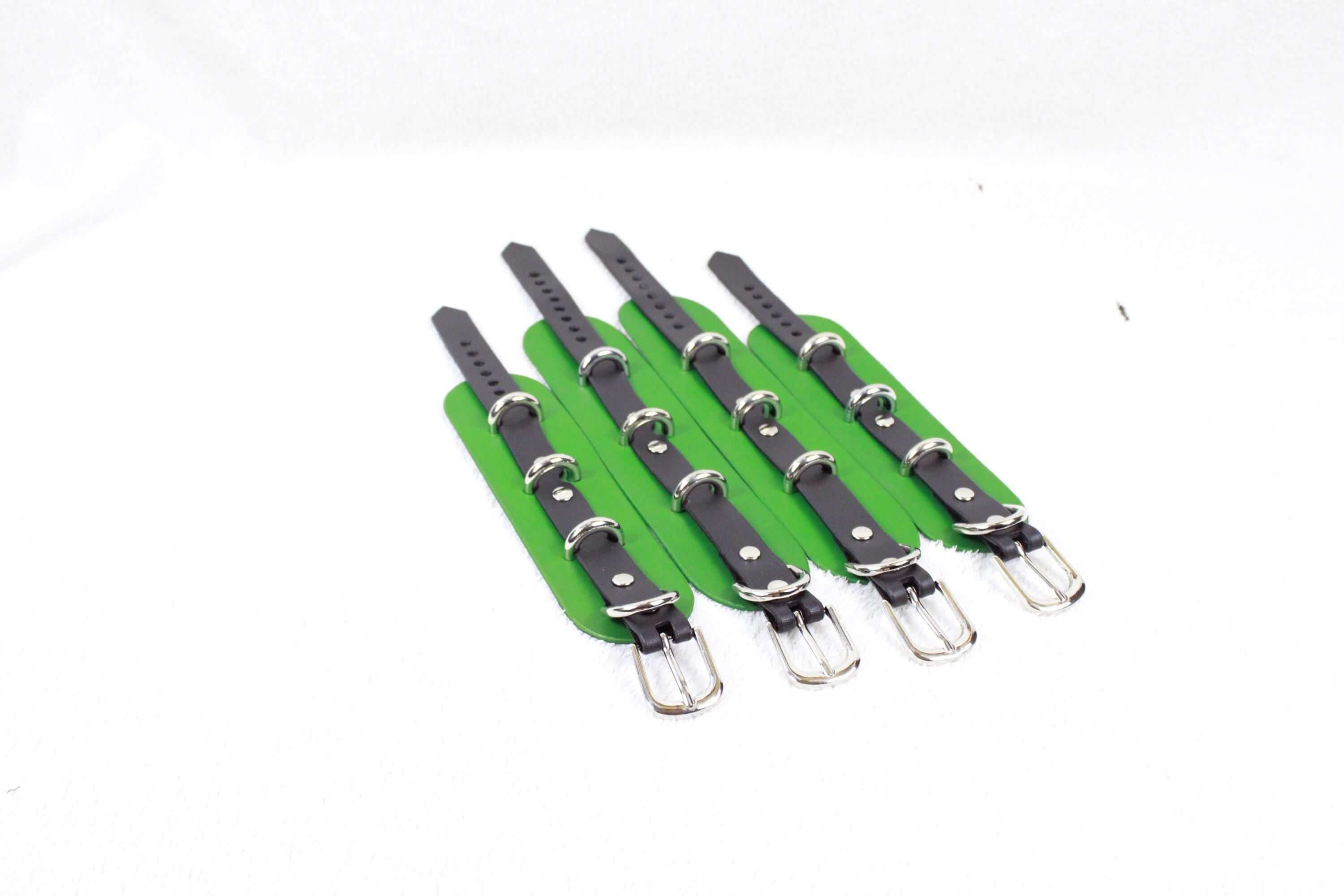 A group of green leather straps with silver buckles, arranged in a row on a white background.