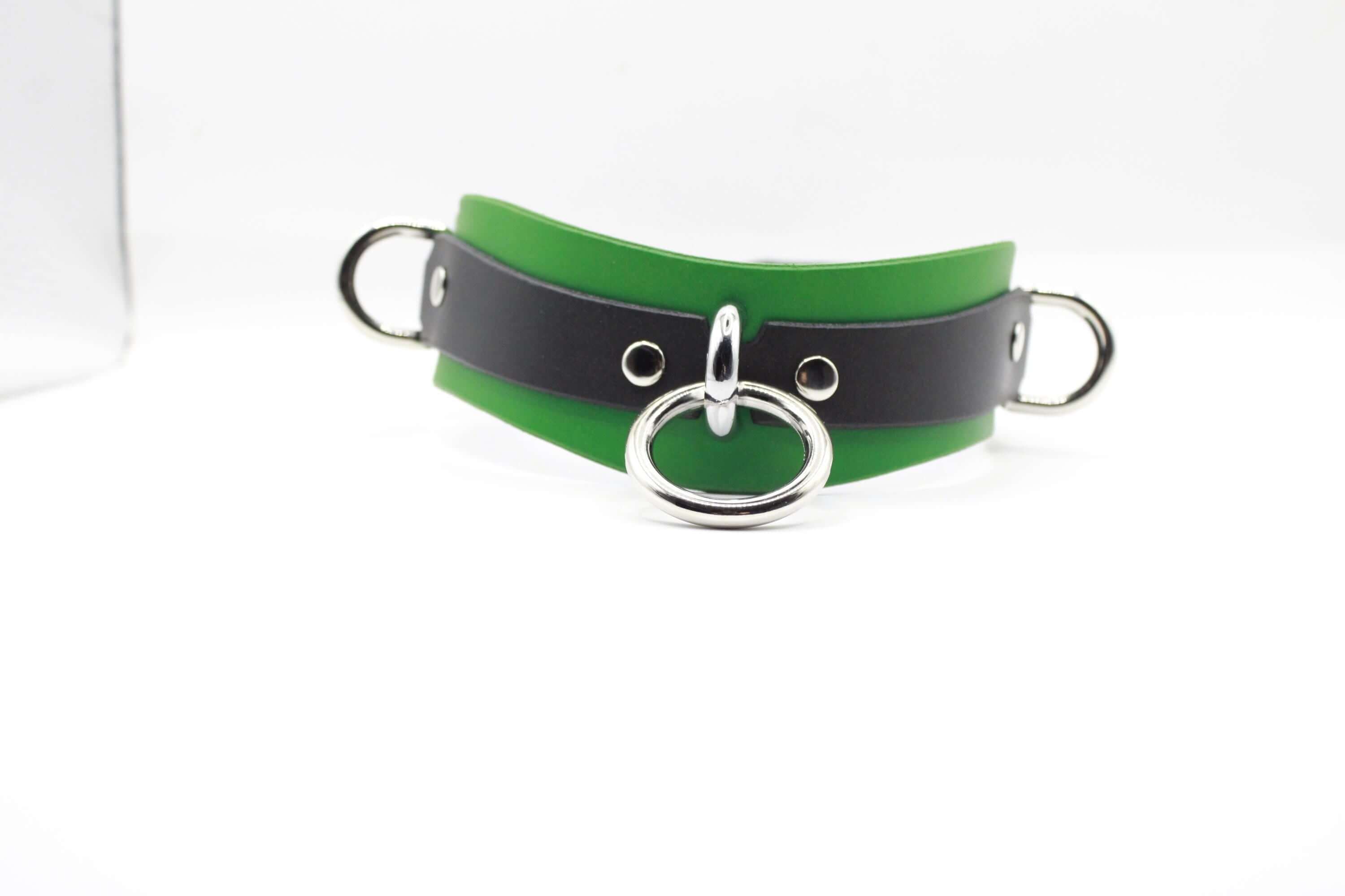 A green and black leather choker necklace with a silver metal ring and two metal rings on either side.