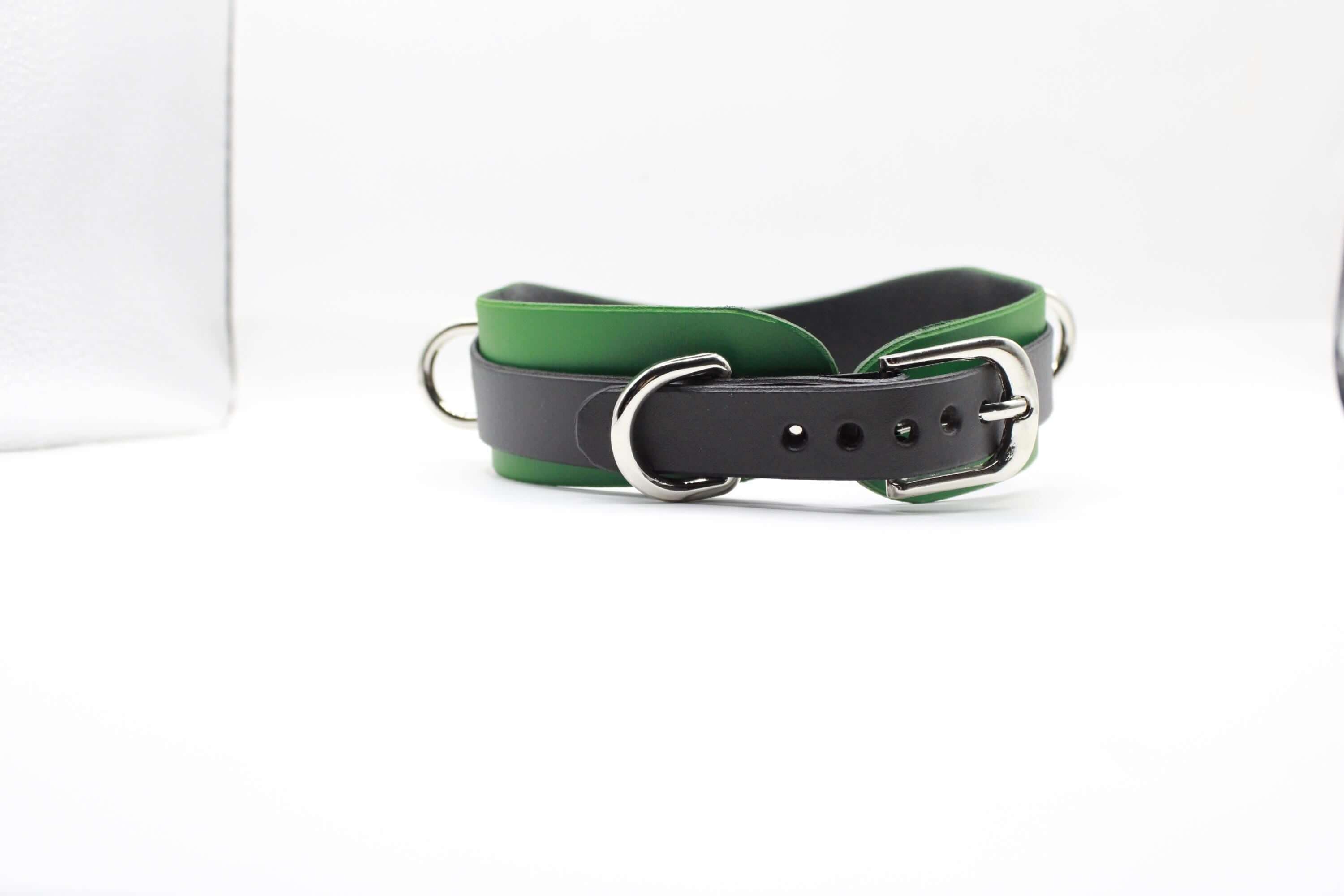 A black and green leather collar with a silver buckle is shown against a white background.