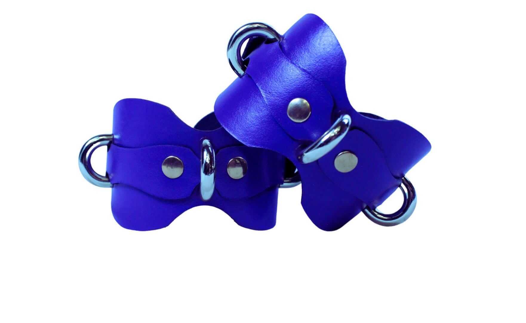 Purple leather ankle cuffs with metal rings, perfect for BDSM bondage gear and submissive lifestyle accessories.