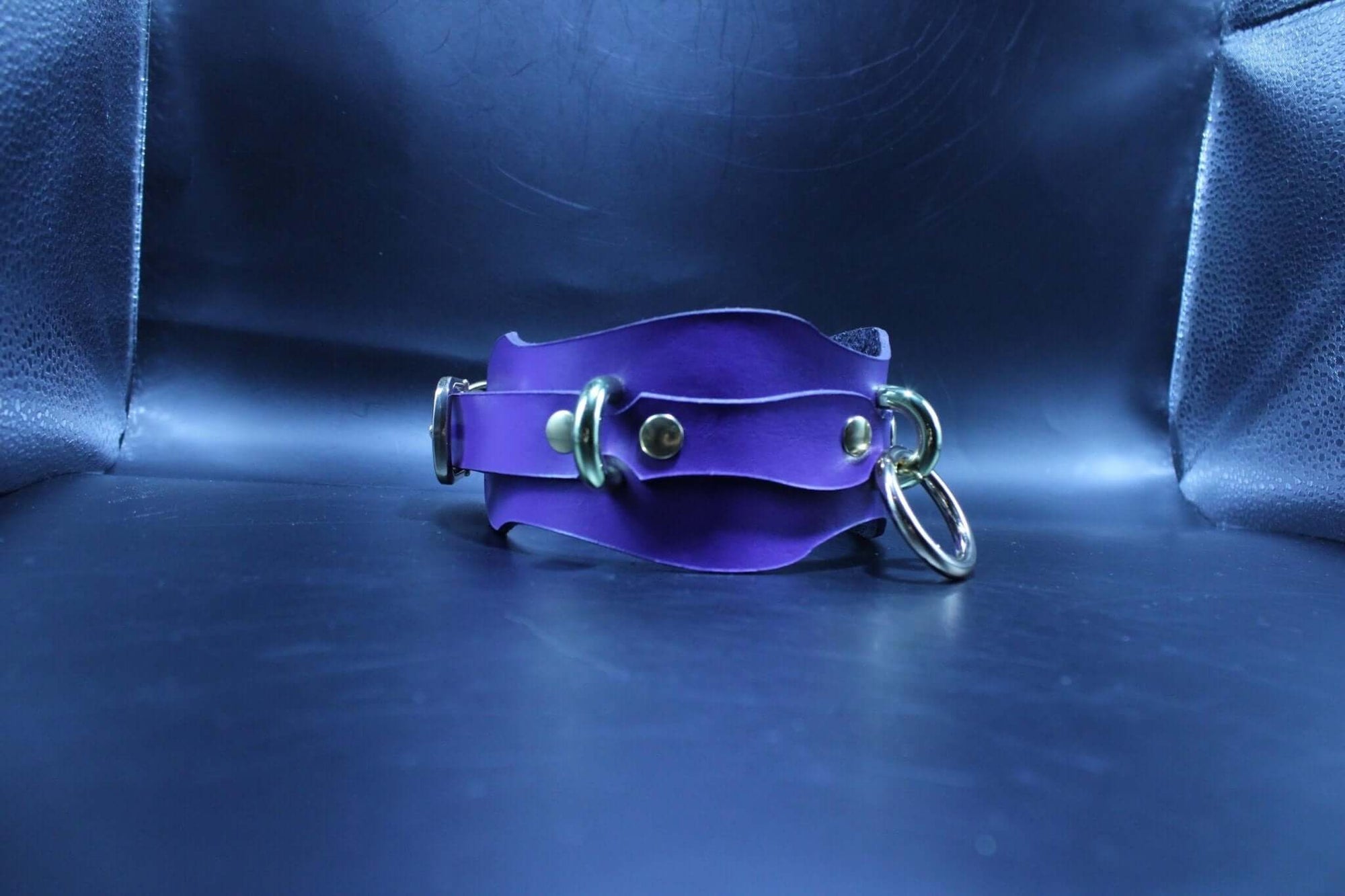 Handmade purple leather submissive collar with O-rings for BDSM play, featuring adjustable design for comfort and style.