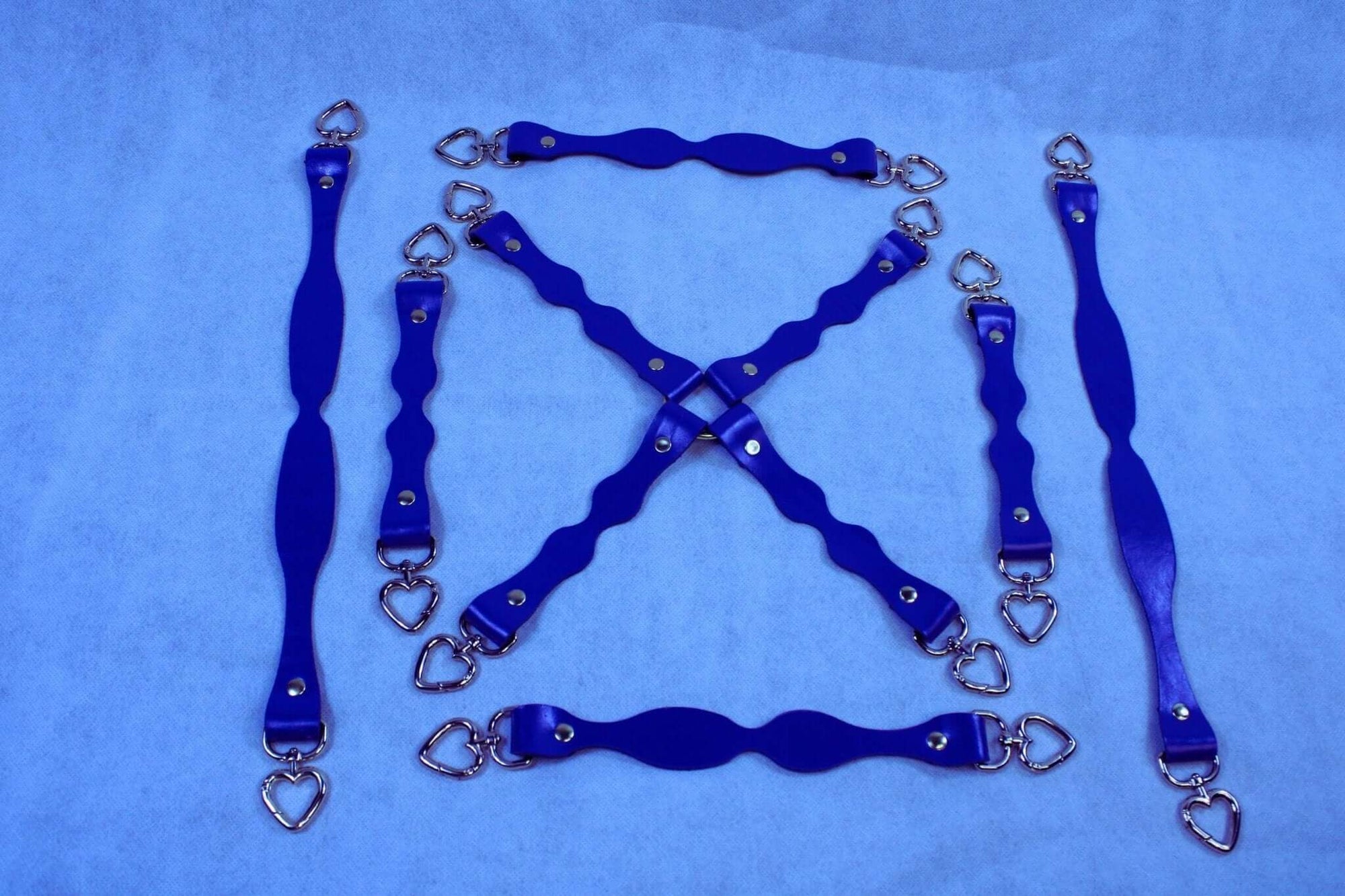 Handmade blue leather BDSM connectors with heart-shaped D-rings for bondage gear and restraint accessories.
