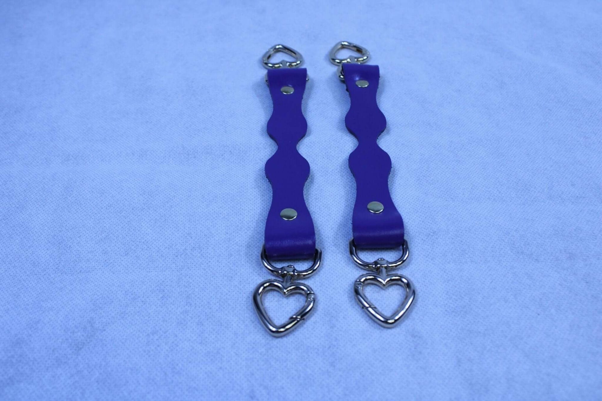 Purple leather BDSM connectors with heart-shaped D-Ring attachments for bondage gear and restraint accessories.