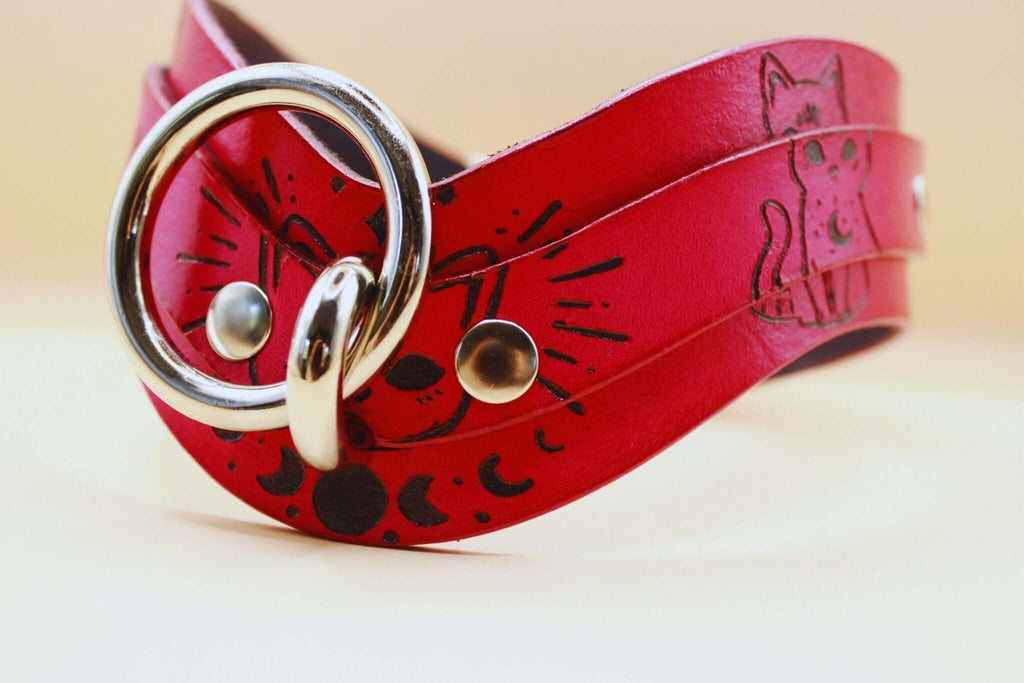 Red leather submissive day collar with cat motifs, perfect for discreet BDSM and daily wear.