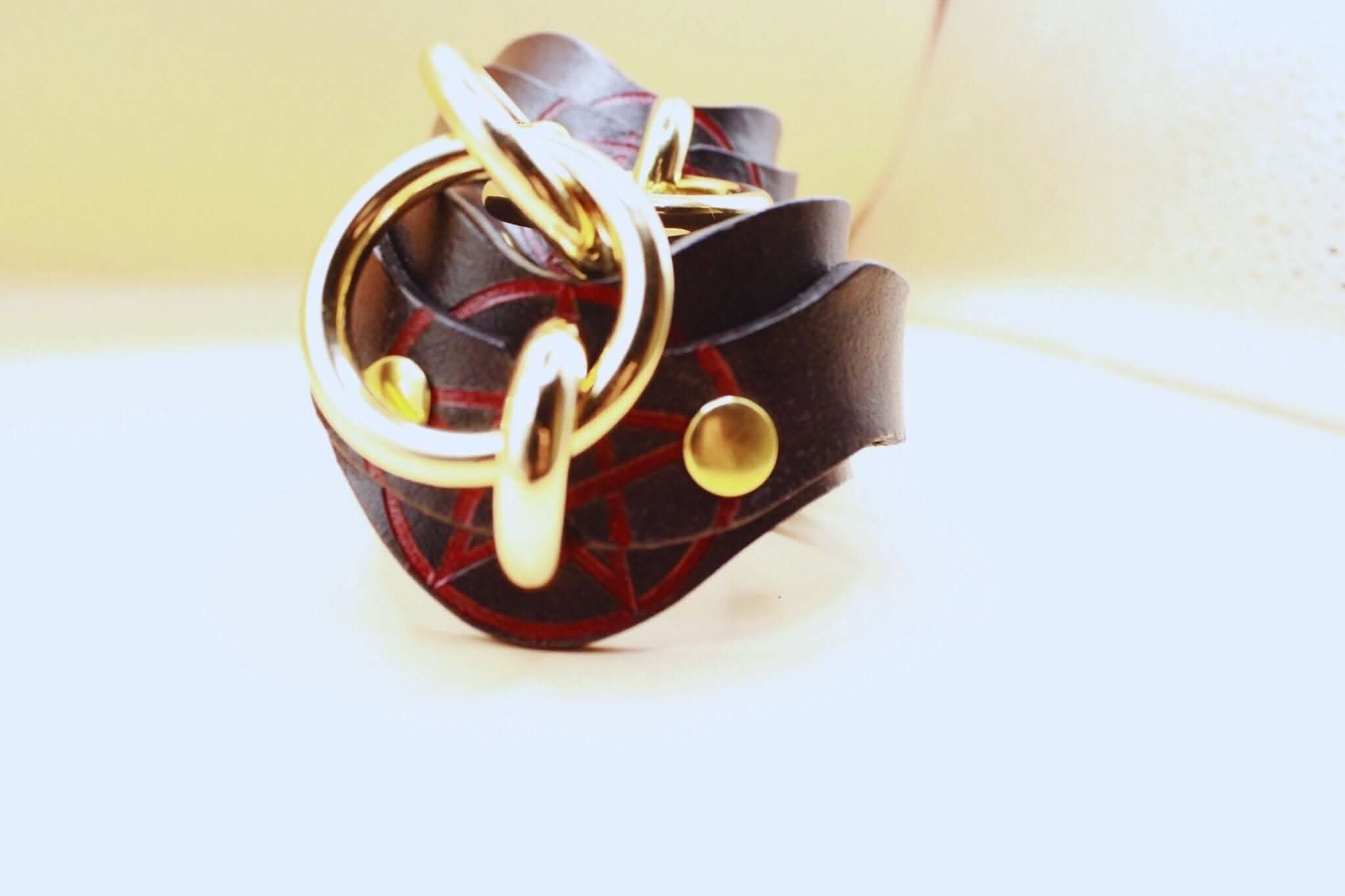 Luxury leather wrist cuff with pentagram design and polished gold hardware for BDSM bondage play.