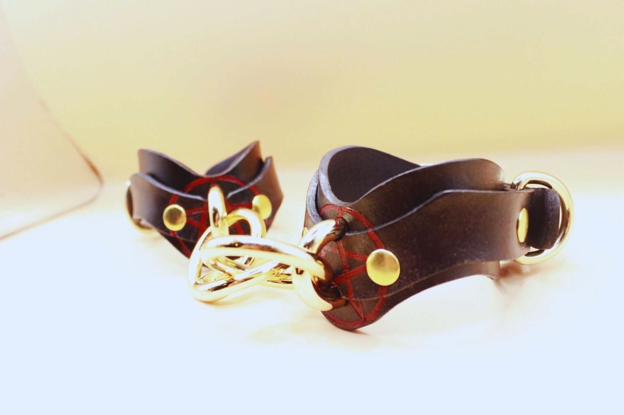 Luxury leather wrist cuffs with gold hardware for BDSM bondage play, perfect for submissives and kinksters.