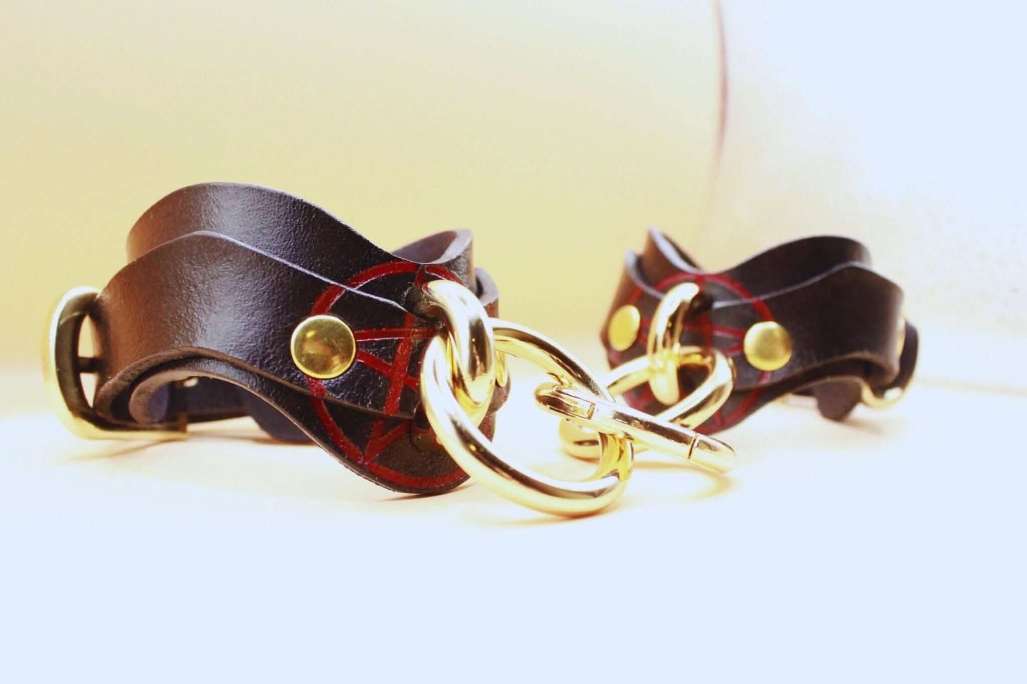 Luxury leather BDSM cuffs with golden hardware, perfect for bondage play and submissive jewelry.
