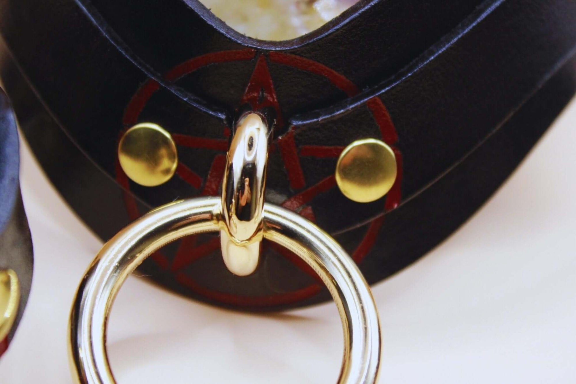 Close-up of a handcrafted pentagram BDSM collar featuring a gold ring and black leather, perfect for discreet day wear.
