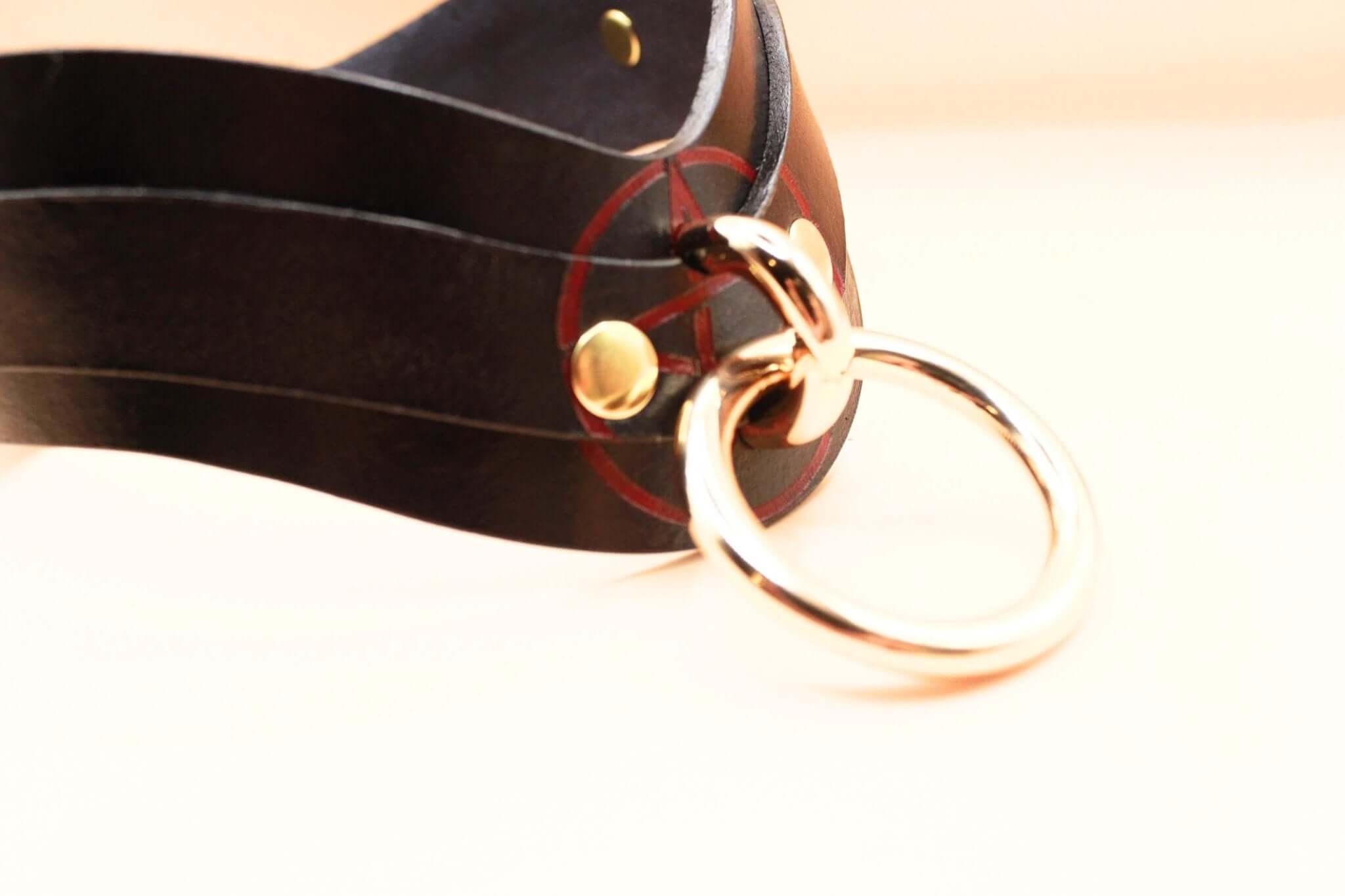 Close-up of a black leather BDSM collar with gold hardware, perfect for submissive jewelry and discreet day collar wear.