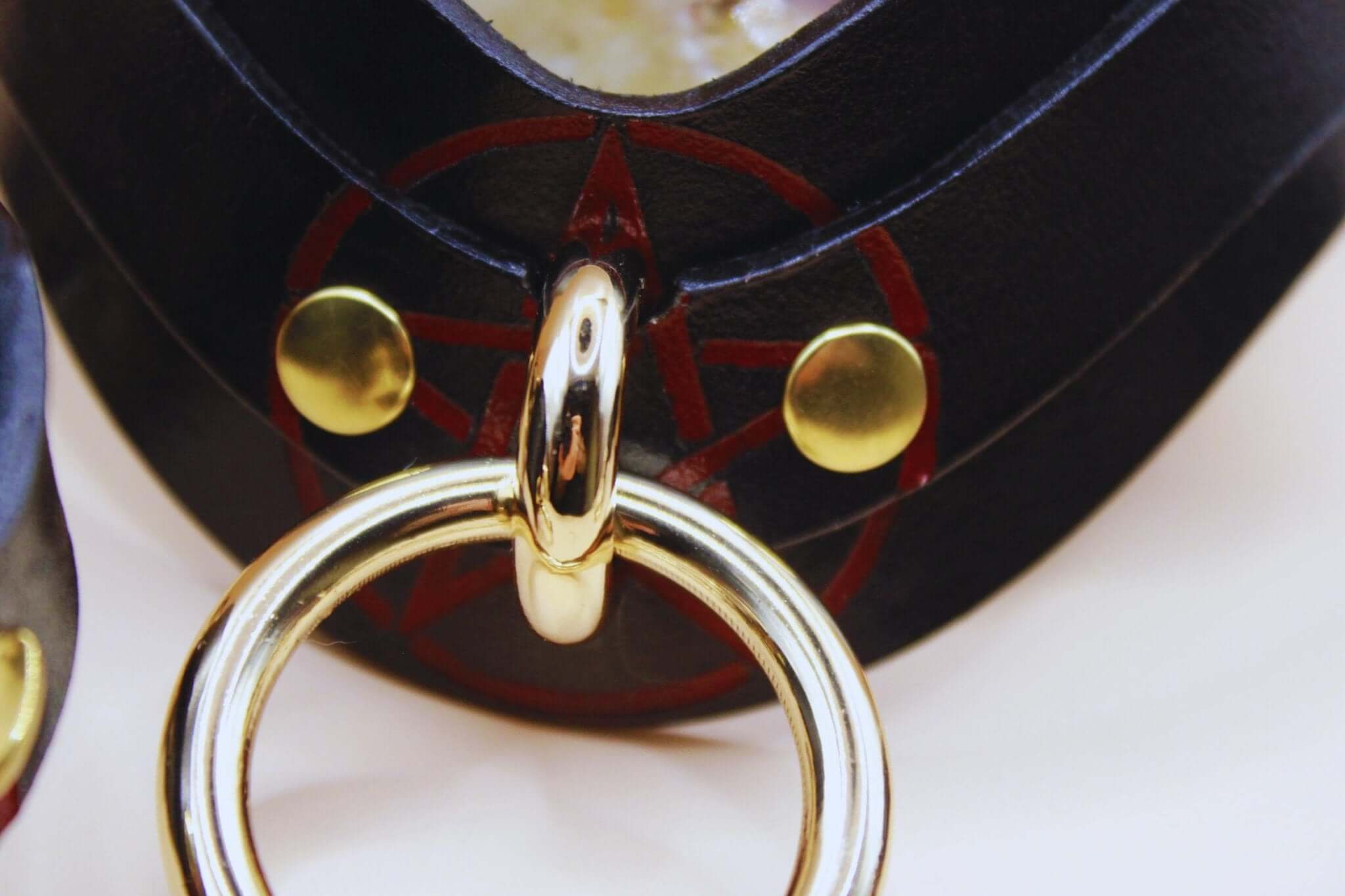 Close-up of a luxurious BDSM collar featuring a pentagram symbol and gold hardware, ideal for submissive play.