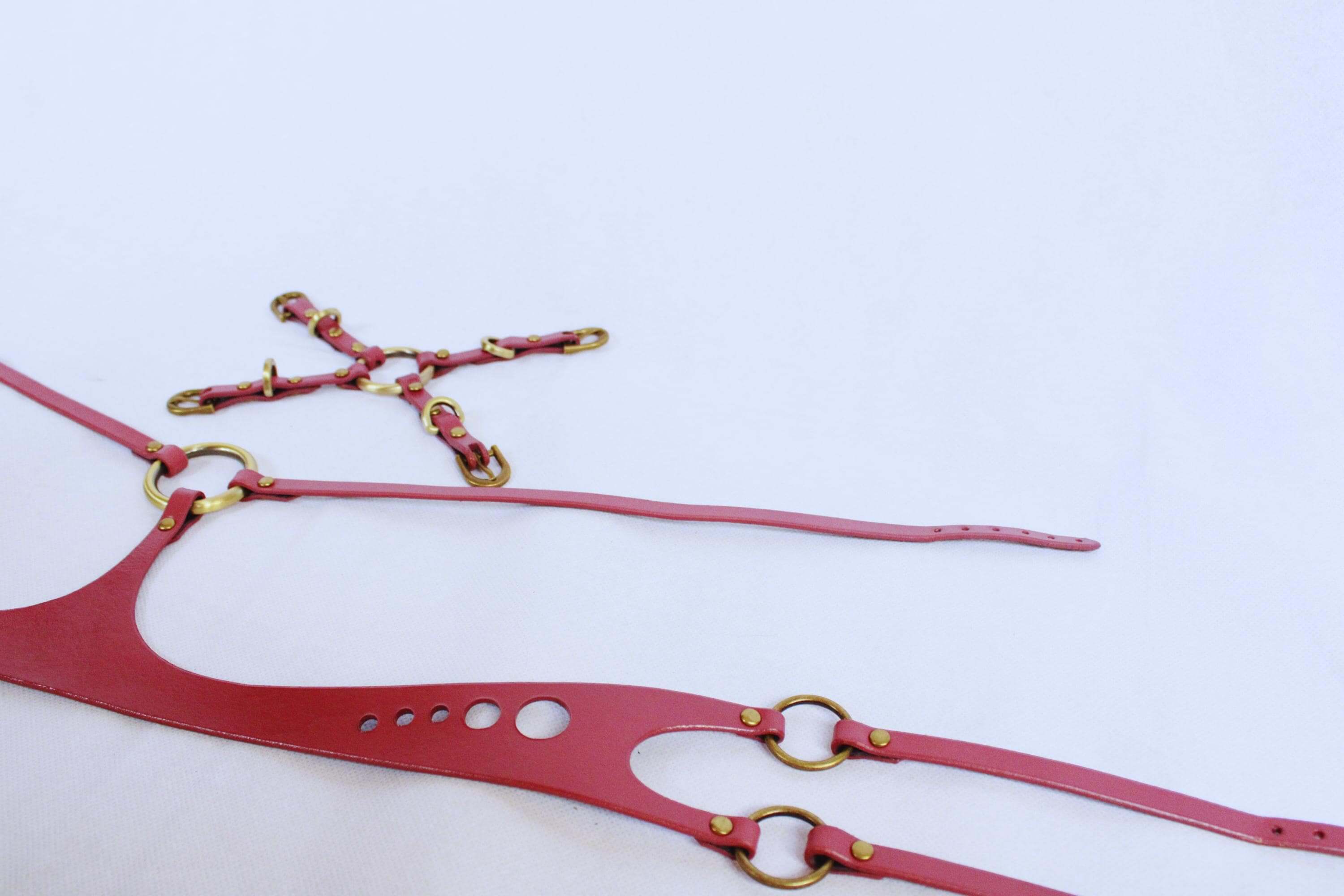 Elegant pink leather BDSM body harness with gold hardware for bondage and sensual play, perfect for accentuating curves.