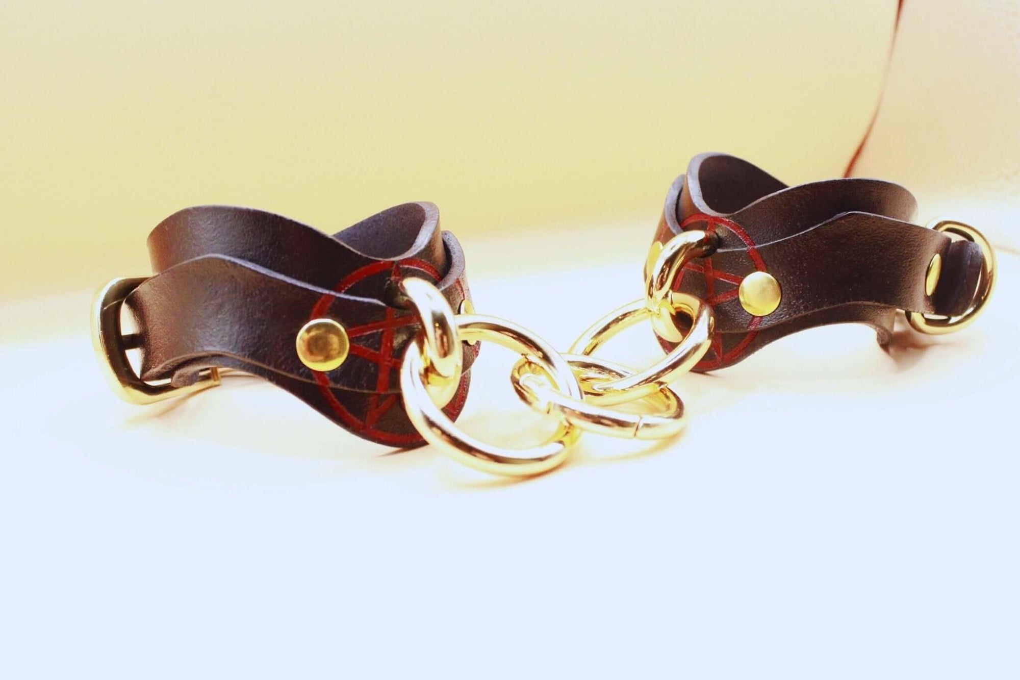 Luxury leather bondage cuffs with gold rings, perfect for BDSM play and submissive jewelry.