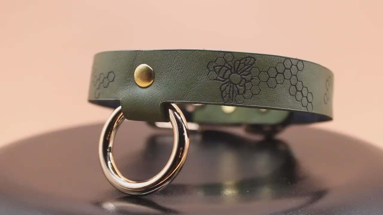 Honeycomb BDSM collar in green leather with decorative bee motif and O-ring, perfect for submissive jewelry and bondage gear.