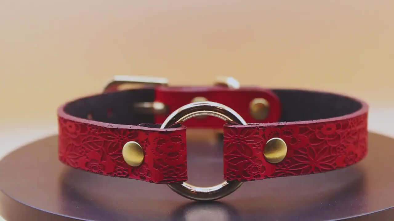 Elegant red floral leather submissive collar with gold O-ring, perfect for BDSM and submissive jewelry enthusiasts.