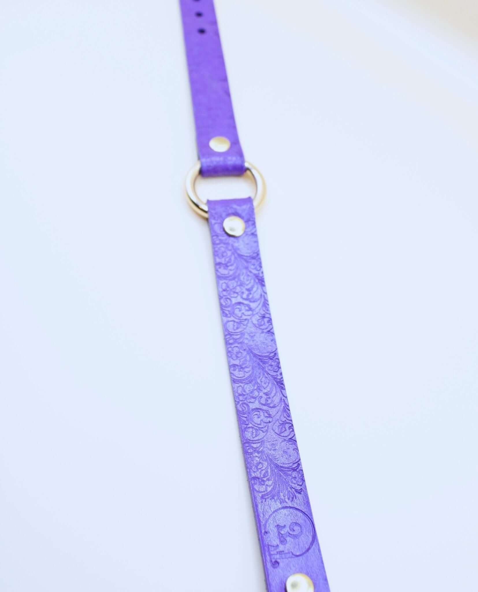 Purple leather BDSM collar with embossed floral design and central O-ring, perfect for submissive jewelry and discreet wear.