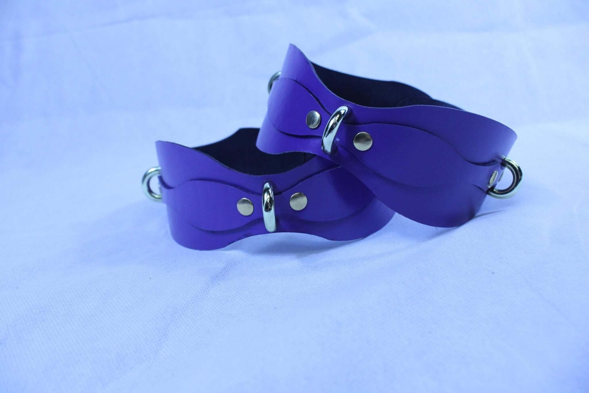 Adjustable purple thigh cuffs in genuine leather, perfect for bondage gear and submissive play.