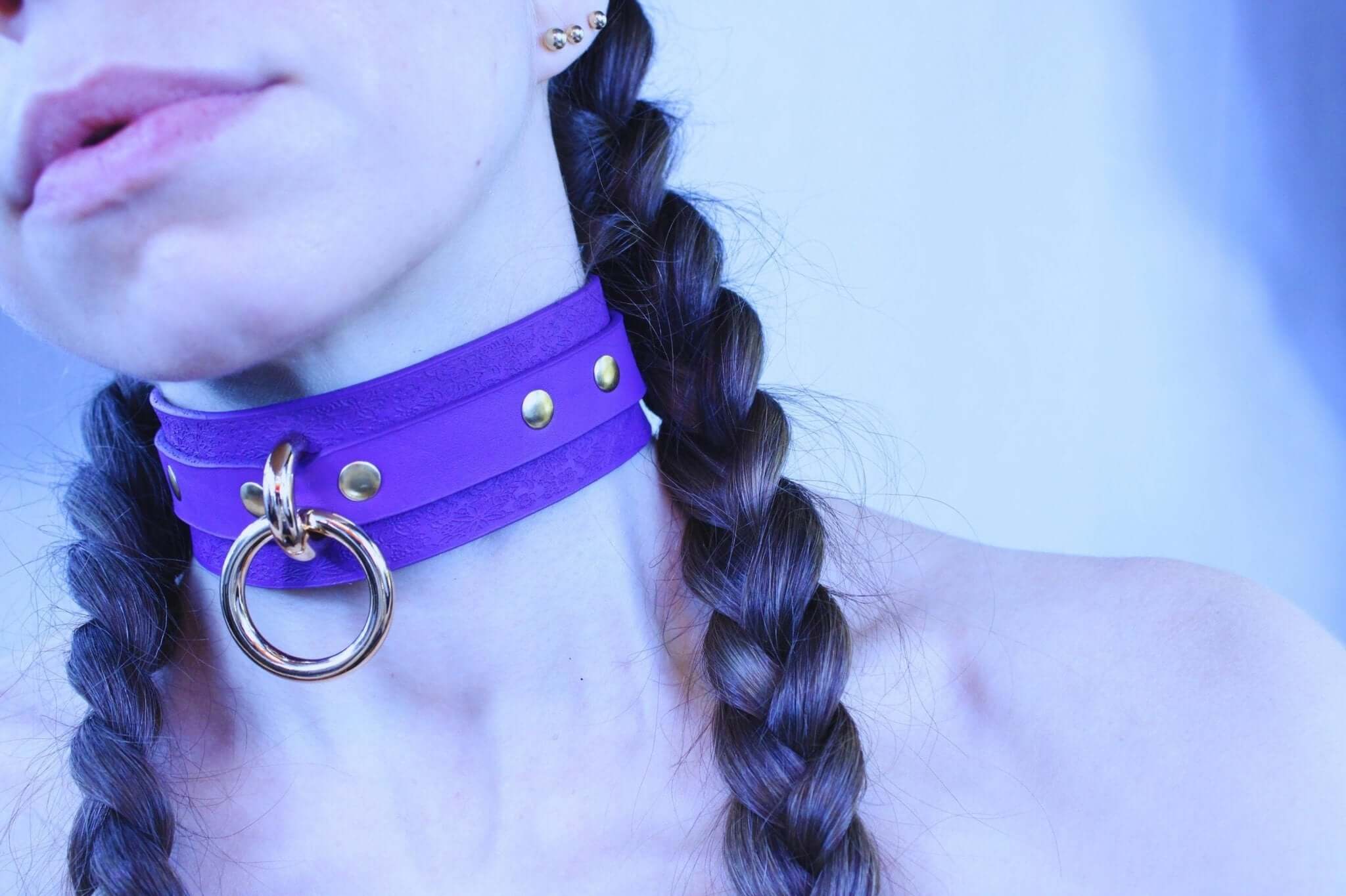 Purple leather choker collar featuring gold studs and a metal ring, perfect for BDSM and discreet day wear.