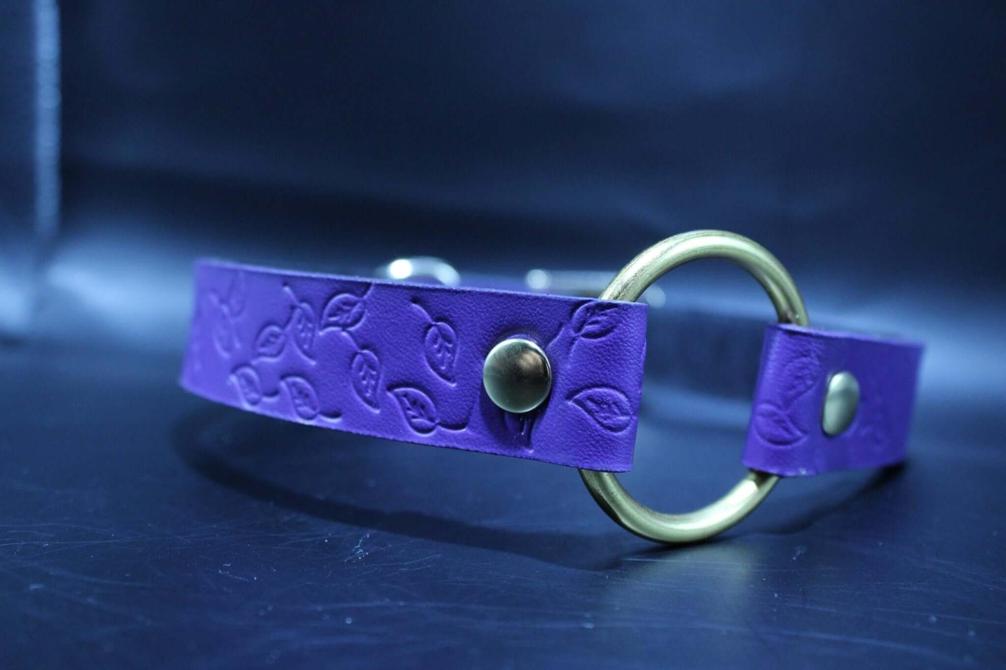 Purple leather submissive collar with embossed leaf pattern and brass O-ring, perfect for BDSM and bondage play.