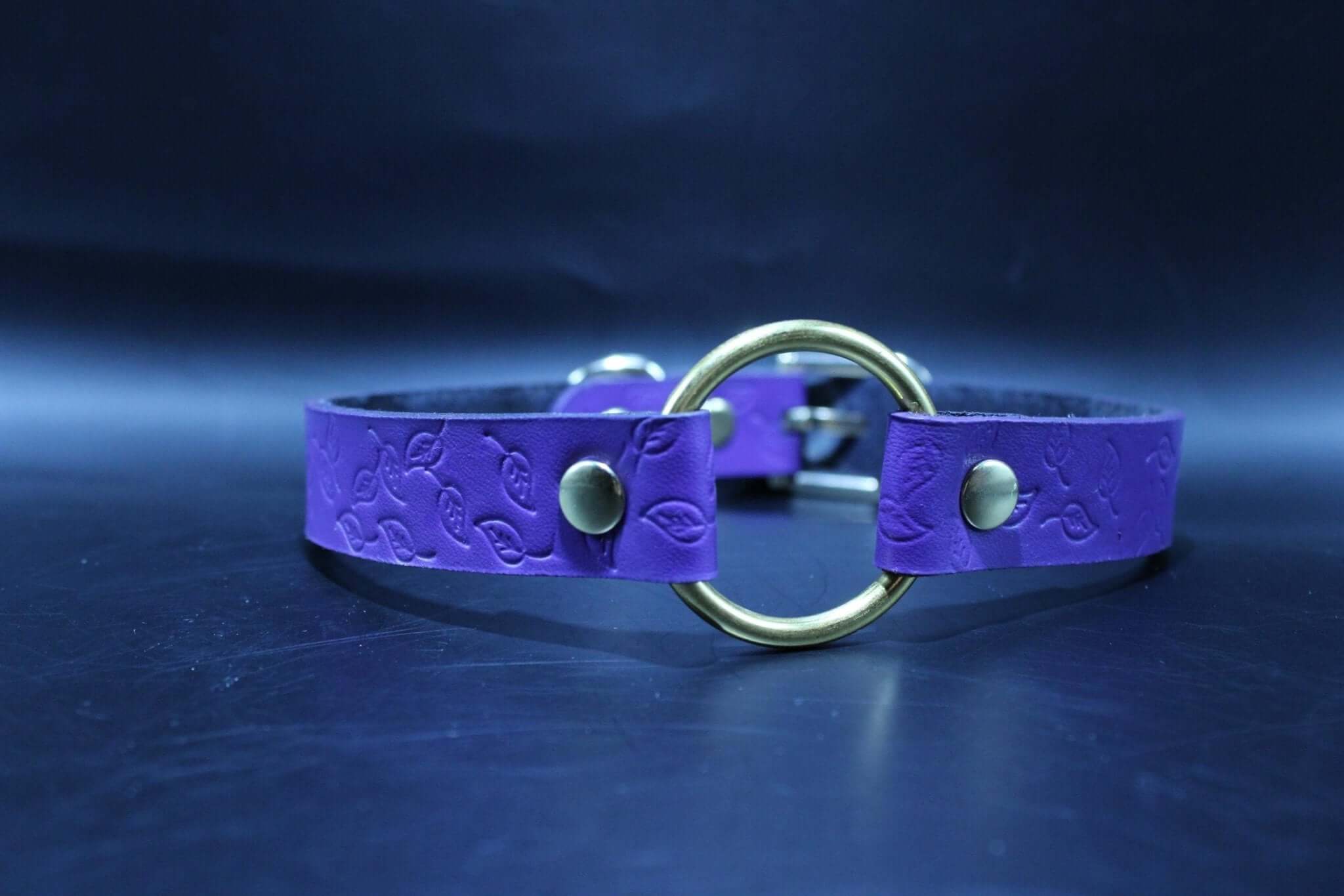 Purple submissive collar with embossed leaf pattern and brass O-ring, ideal for BDSM and petplay dynamics.
