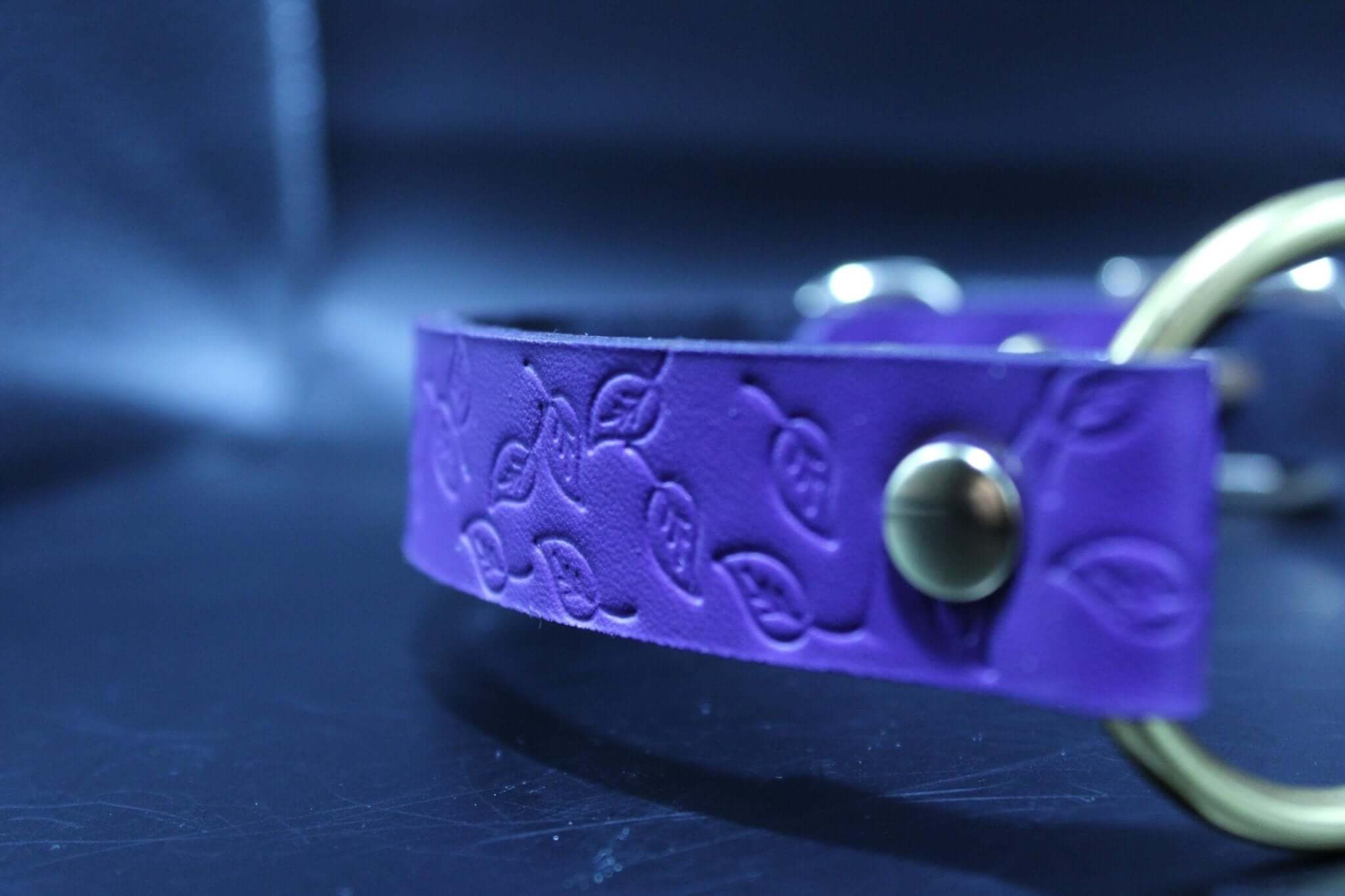 Purple leather submissive collar with embossed leaf pattern and brass O-ring for BDSM and petplay.