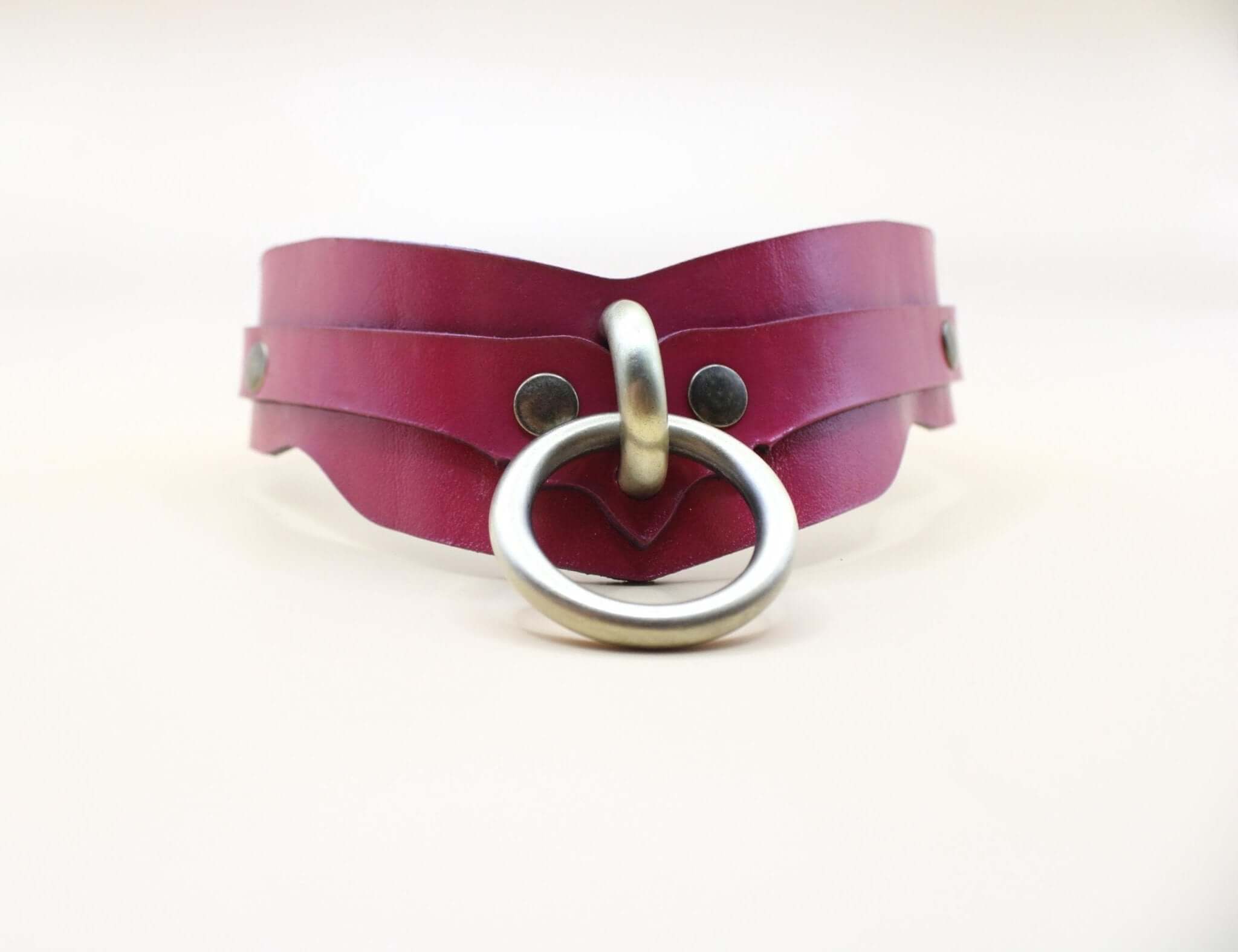 Raspberry leather BDSM collar with double-strap design and brass O-ring for submissive jewelry and bondage gear.