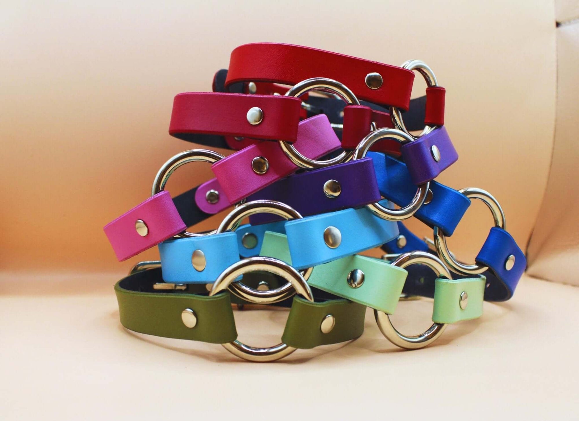Colorful leather collars stacked with metal rings, ideal for bdsm, bondage, and submissive jewelry.