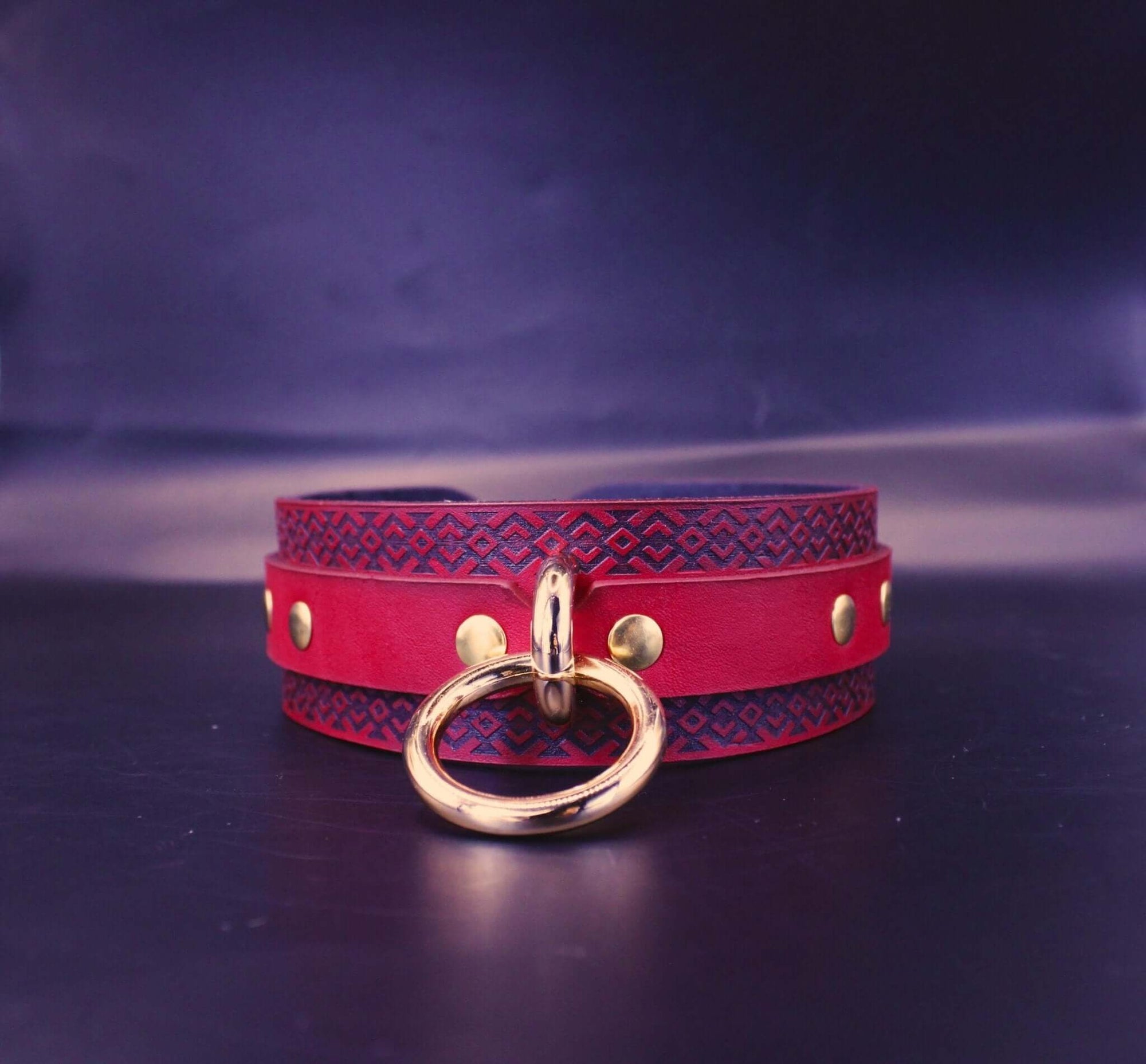 Red BDSM collar with tribal pattern and golden ring, ideal for submissive and bondage play.