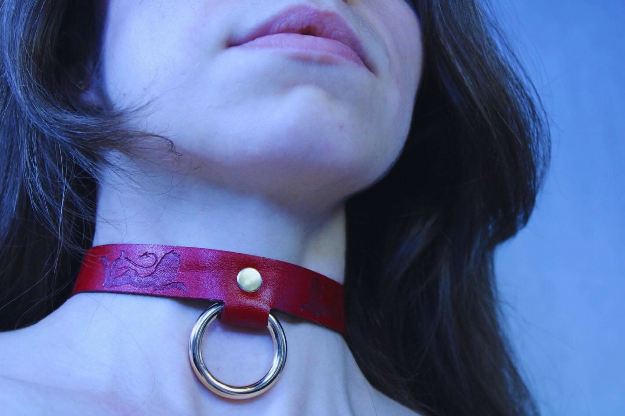 Close-up of a handcrafted red leather submissive collar with O-ring, perfect BDSM jewelry for passion and play.