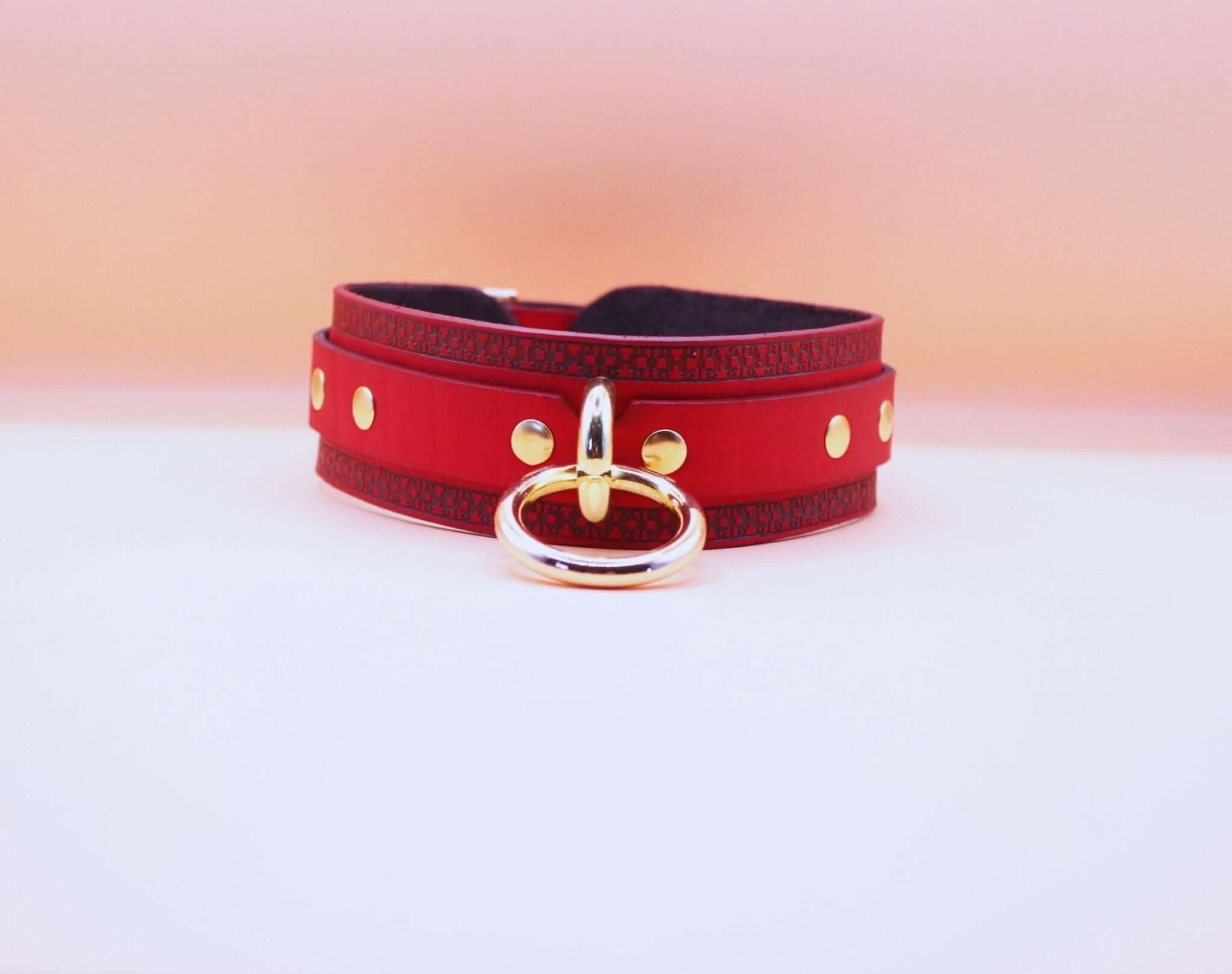 Red BDSM posture collar with golden ring and geometric engraving, perfect for submissive elegance and bondage play.