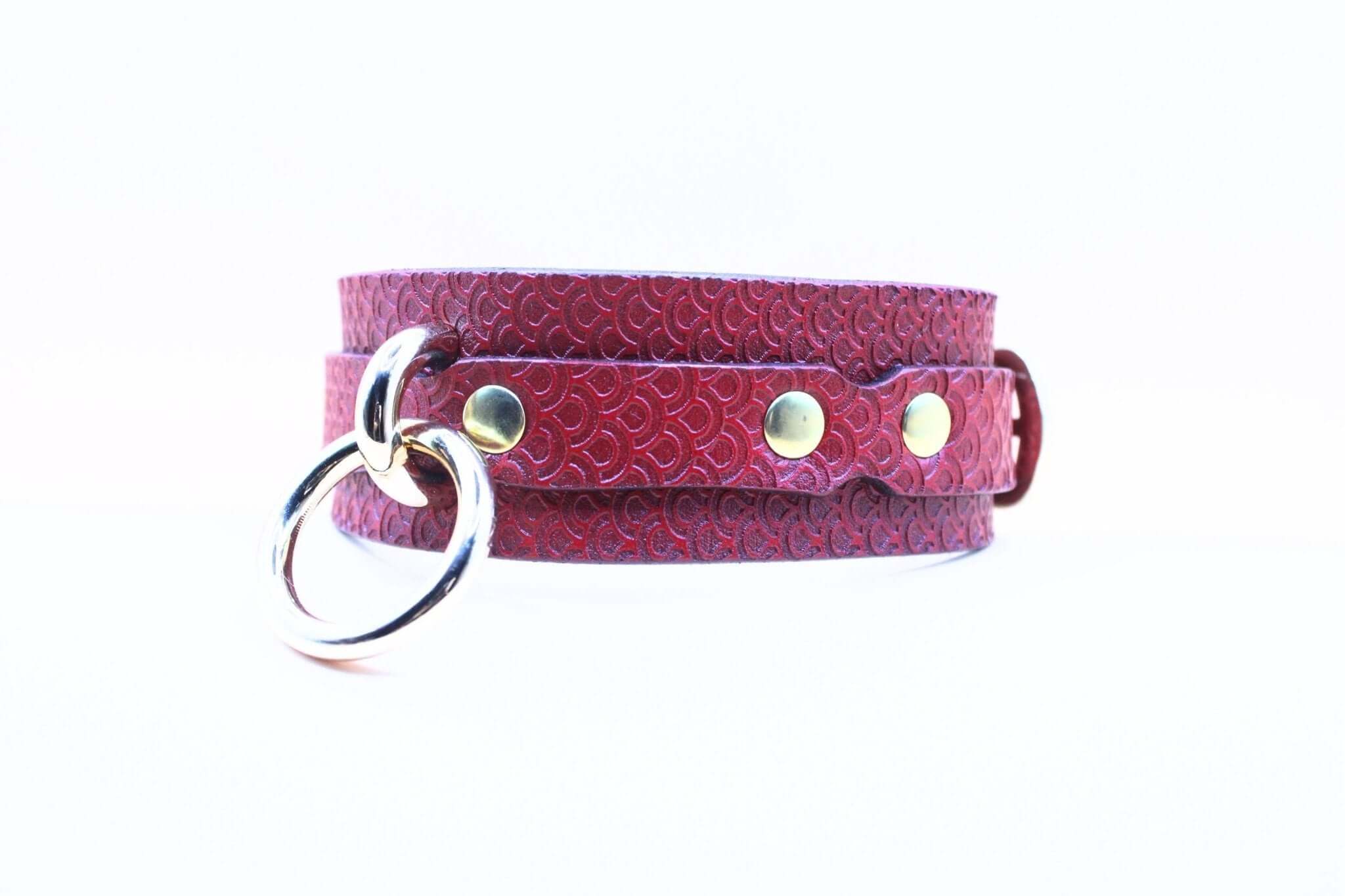 Deep crimson red leather submissive collar with embossed pattern and silver O-ring, ideal for BDSM and bondage use.