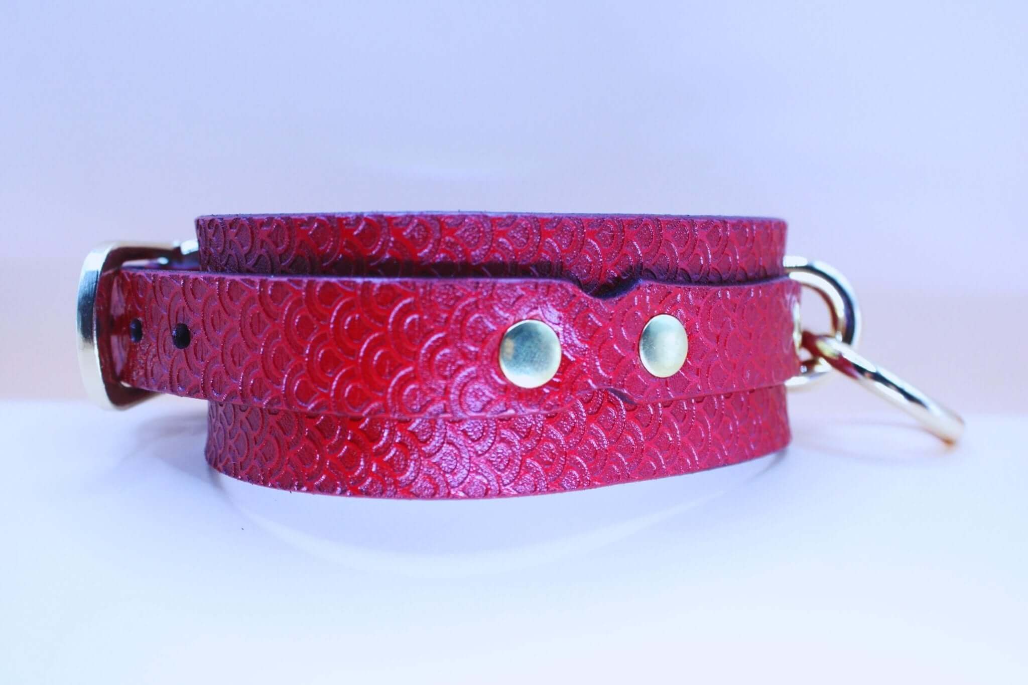 Red leather submissive collar with embossed pattern and O-ring, perfect for bondage and bdsm jewelry.