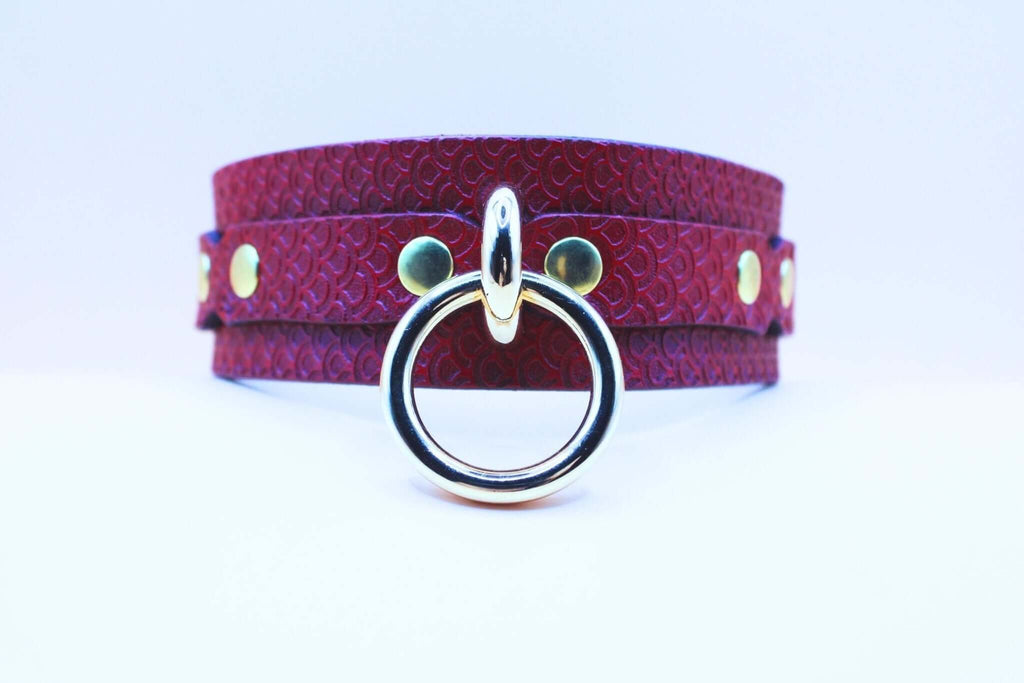 Red leather BDSM collar with embossed pattern and silver O-ring, perfect for submissive jewelry and bondage gear.