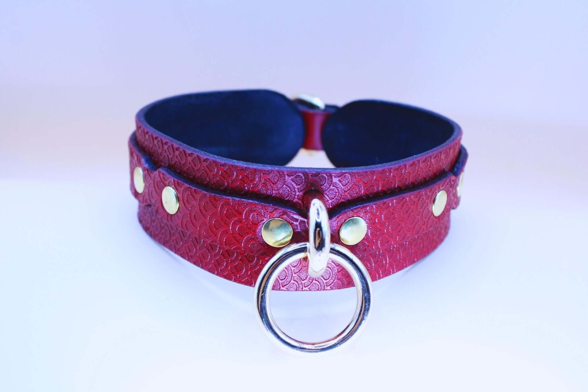 Red leather submissive collar with embossed pattern and large silver O-ring, perfect for BDSM and erotic wear.