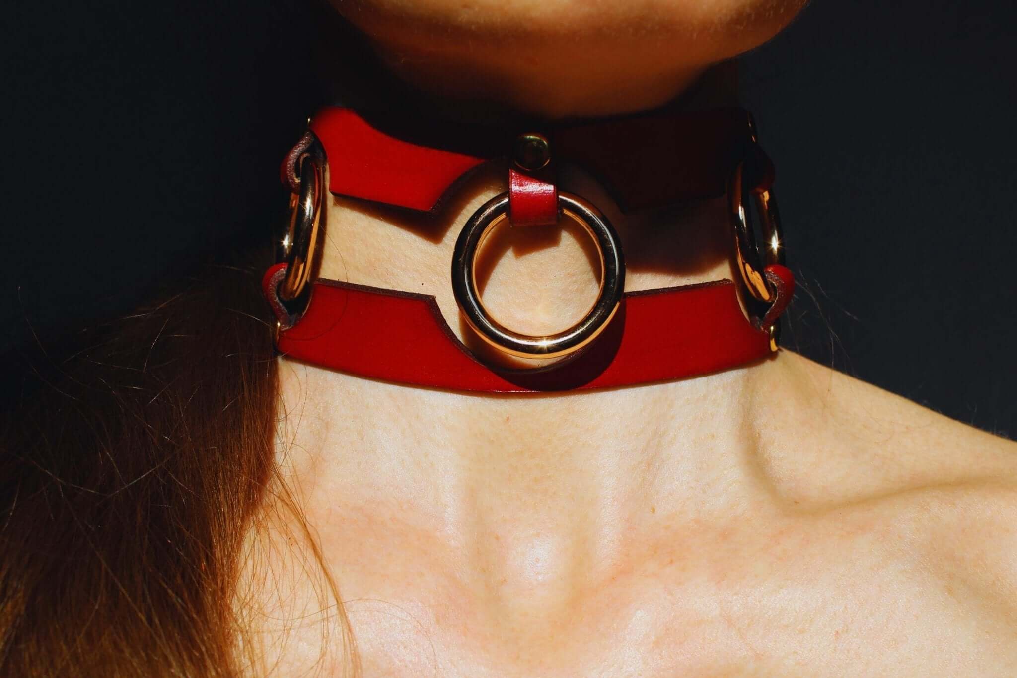 Bold red leather bondage collar with gold rings, perfect for submissive jewelry and BDSM play.