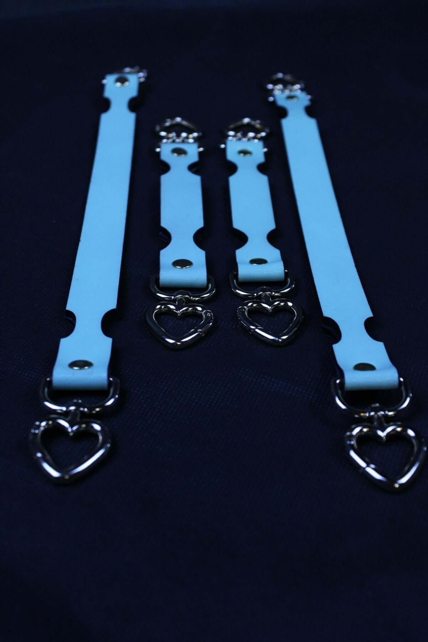 Blue leather BDSM connector straps with heart-shaped metal links for secure bondage play.