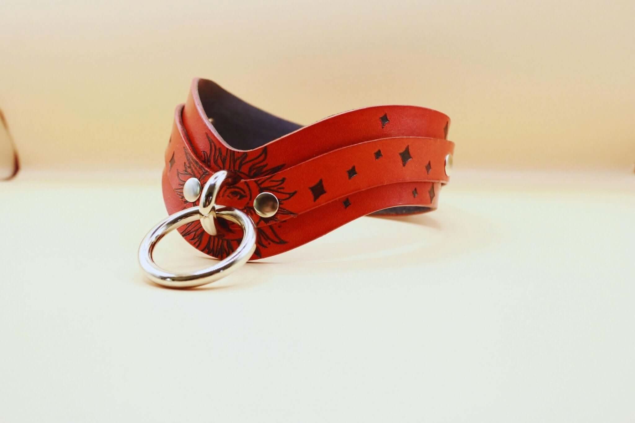 Sun Design BDSM collar in red leather, featuring decorative stars and a metal ring, perfect for discreet submissive jewelry.