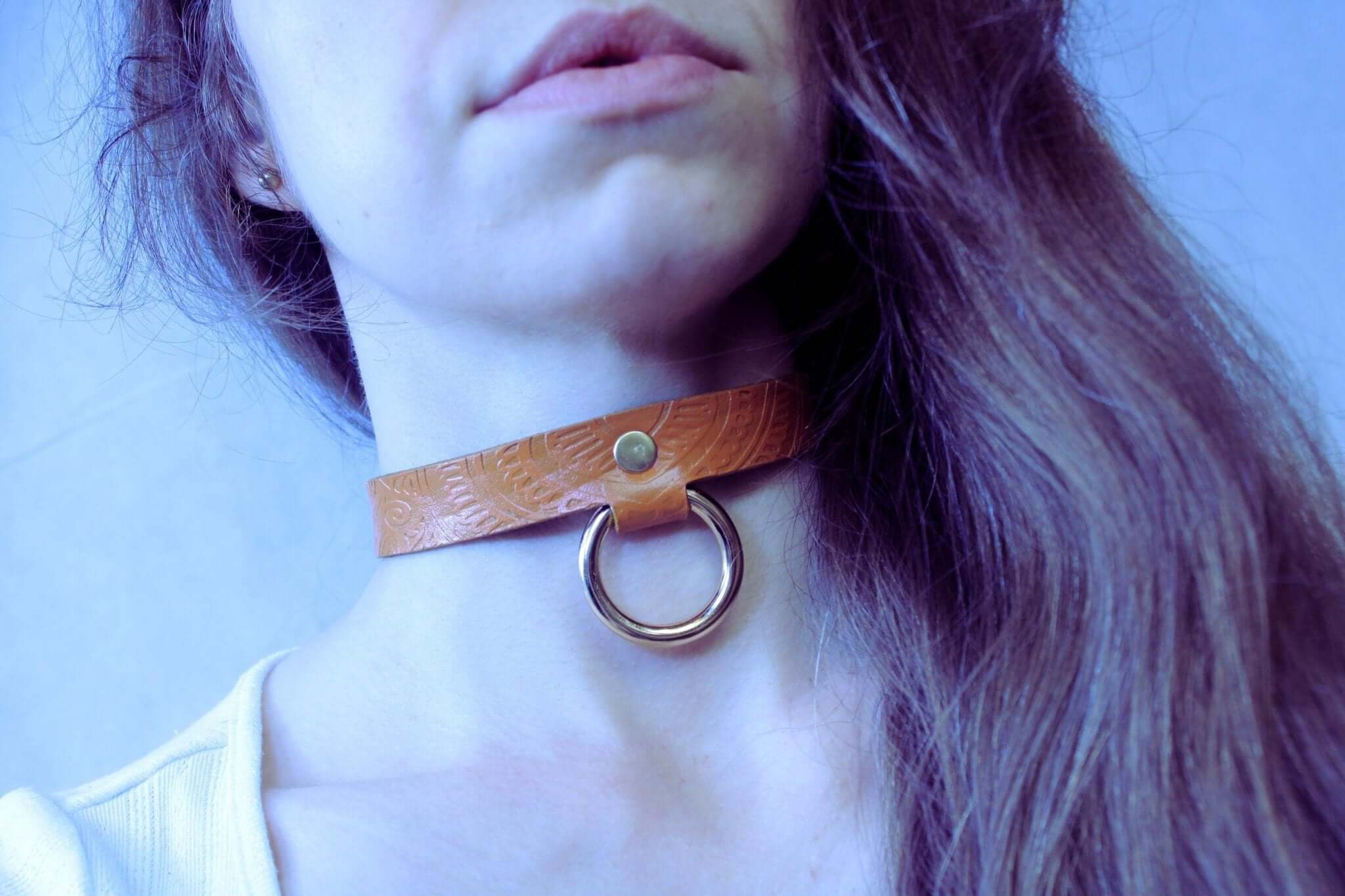 Tan leather BDSM collar with an O-ring, embodying elegance and submission for discreet day wear.