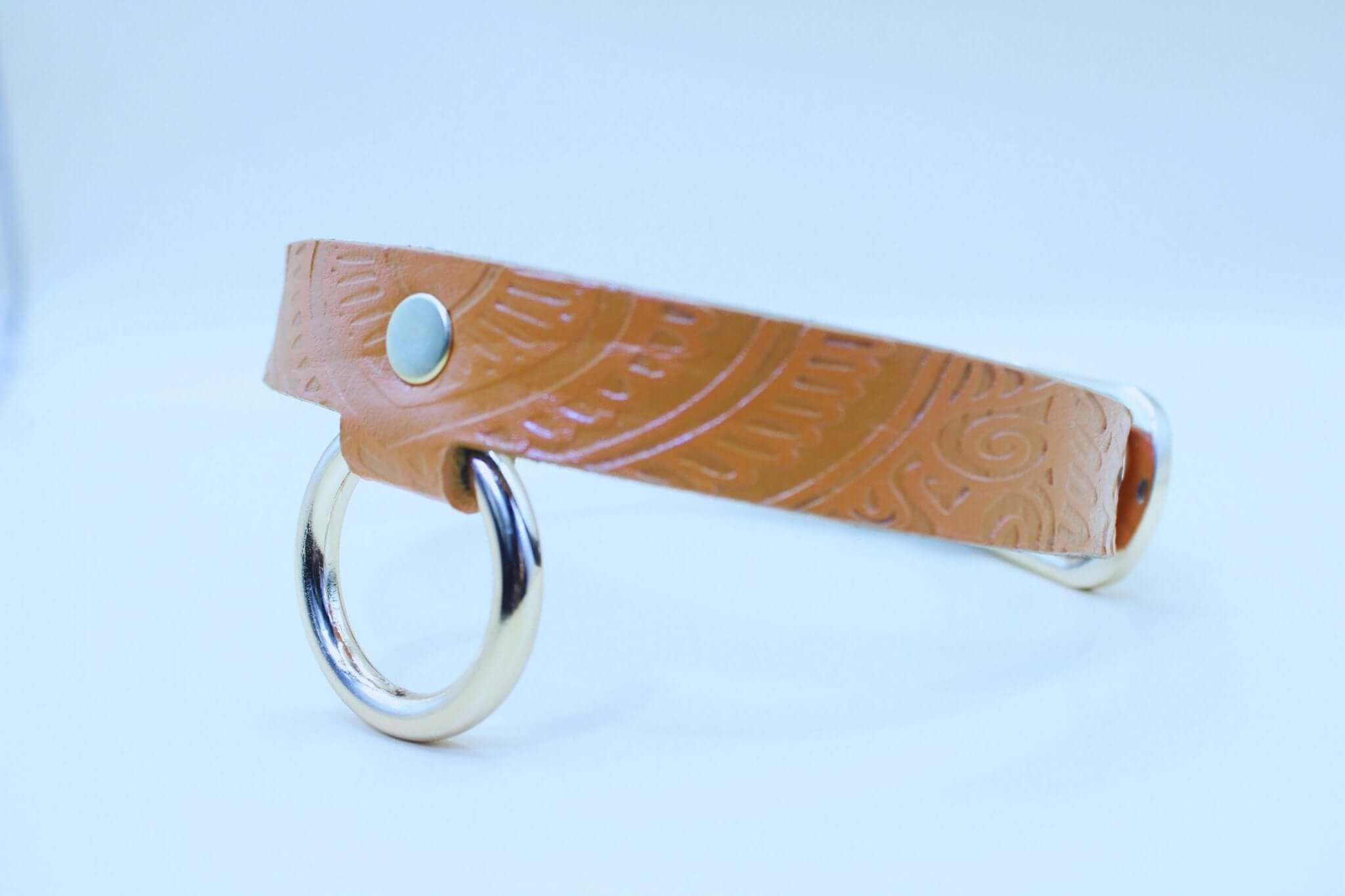 Tan leather BDSM collar with embossed patterns and metal rings, ideal for submissive jewelry and bondage gear.