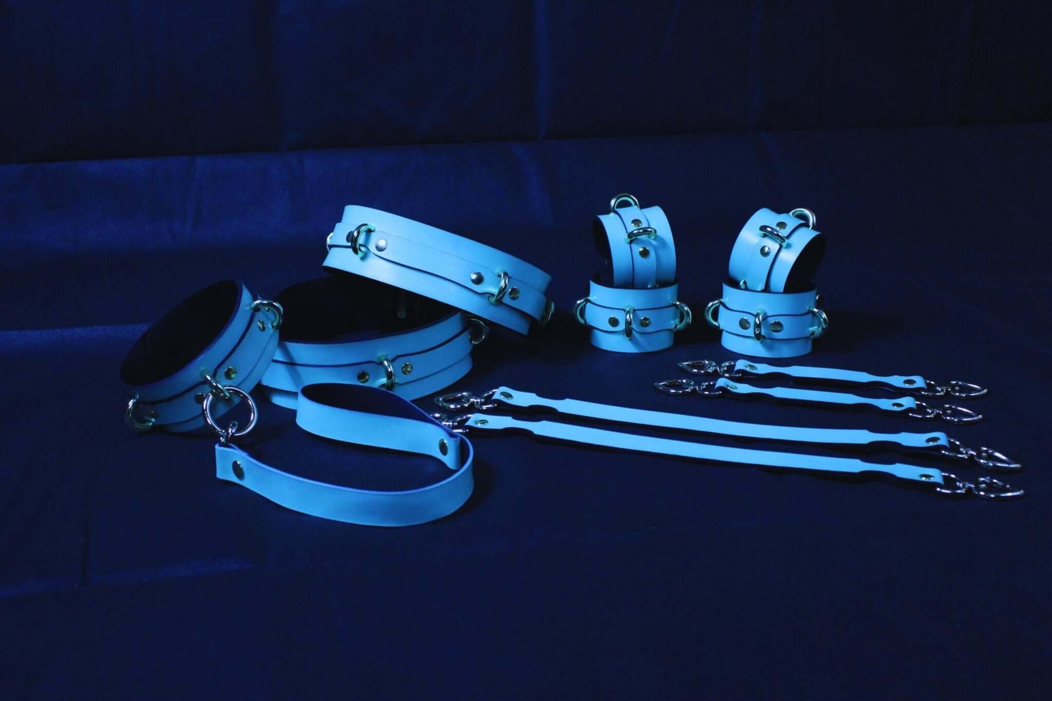Luxury BDSM bondage gear set featuring blue leather cuffs, collar, connectors, and straps for submissive play and restraint.