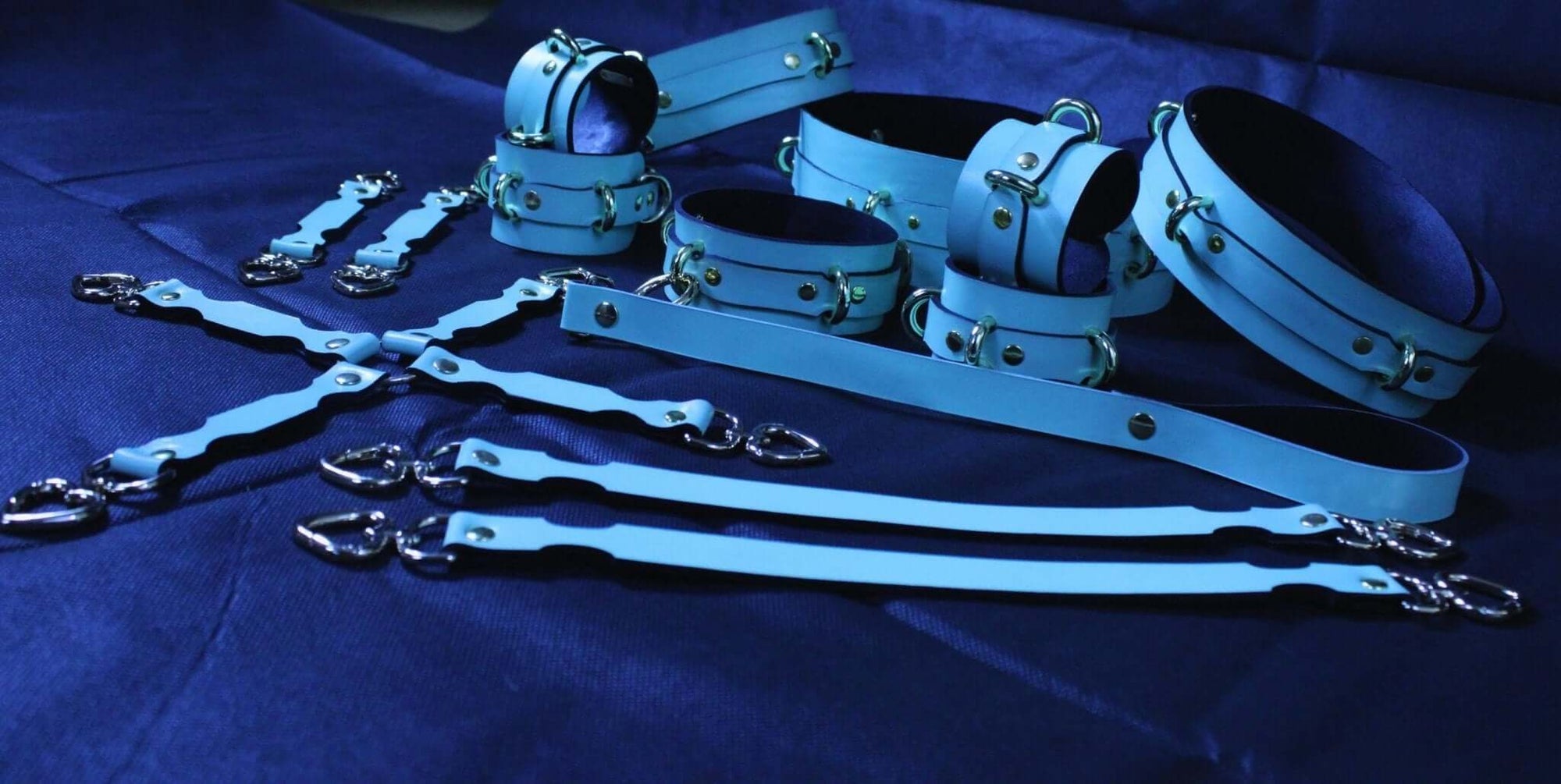 BDSM bondage gear set featuring blue leather cuffs, collars, and connectors for submissive play and erotic exploration.
